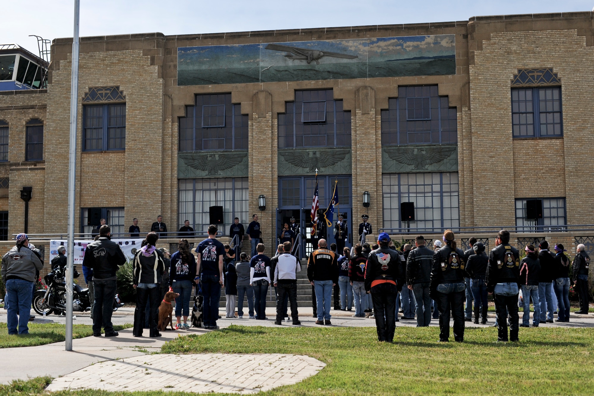 Service members, retirees and city locals stand while McConnell Air Force Base, Kan., honor guard present the American flag, May 17, 2014, at the Kansas Aviation Museum, Wichita, Kan. Motorcyclists participated in the McConnell AFB Company Grade Officers Council’s first Ride to Honor fundraiser event. Proceeds were donated to the Folds of Honor Foundation to help support families of military members who were wounded or killed in action. (U.S. Air Force photo/Airman 1st Class David Bernal del Agua)