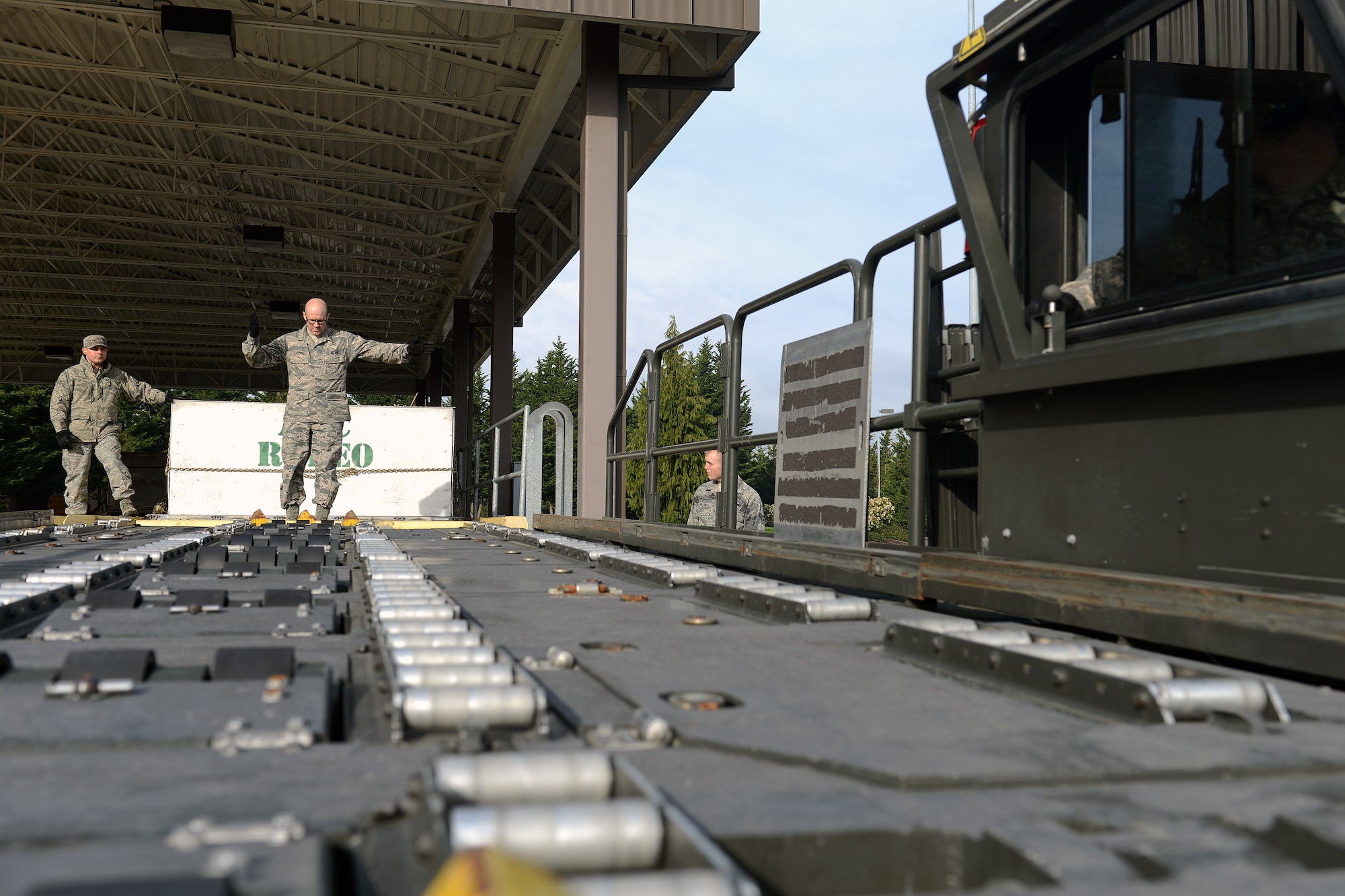 Tech. Sgt. Gregory Stucky (left), 62nd Aerial Port Squadron Port Dawg University NCO in charge, watches Staff Sgt. Nicholas Gustin (center), 86th Aerial Port Squadron air transportation specialist, marshal the driver of Halverson Loader during a PDU course March 13, 2014, at Joint Base Lewis-McChord, Wash. PDU provides an independent three day course to certify students on the Halverson Loader in addition to its 90-day course for new Airmen. (U. S. Air Force photo/Airman 1st Class Jacob Jimenez)