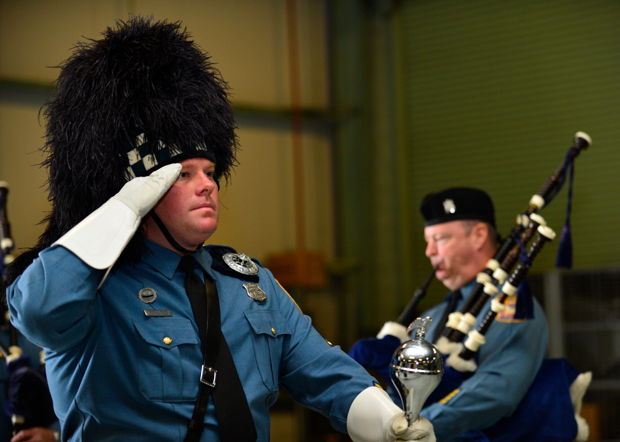 Douglas Duke, Delaware State Police senior dispatcher, salutes during a rendition of the national anthem during a retreat ceremony May 16, 2014 at Dover Air Force Base, Del. Duke is a member of the Delaware State Police Pipes and Drums Unit who attended and performed during the retreat. (U.S. Air Force photo/Airman 1st Class William Johnson)