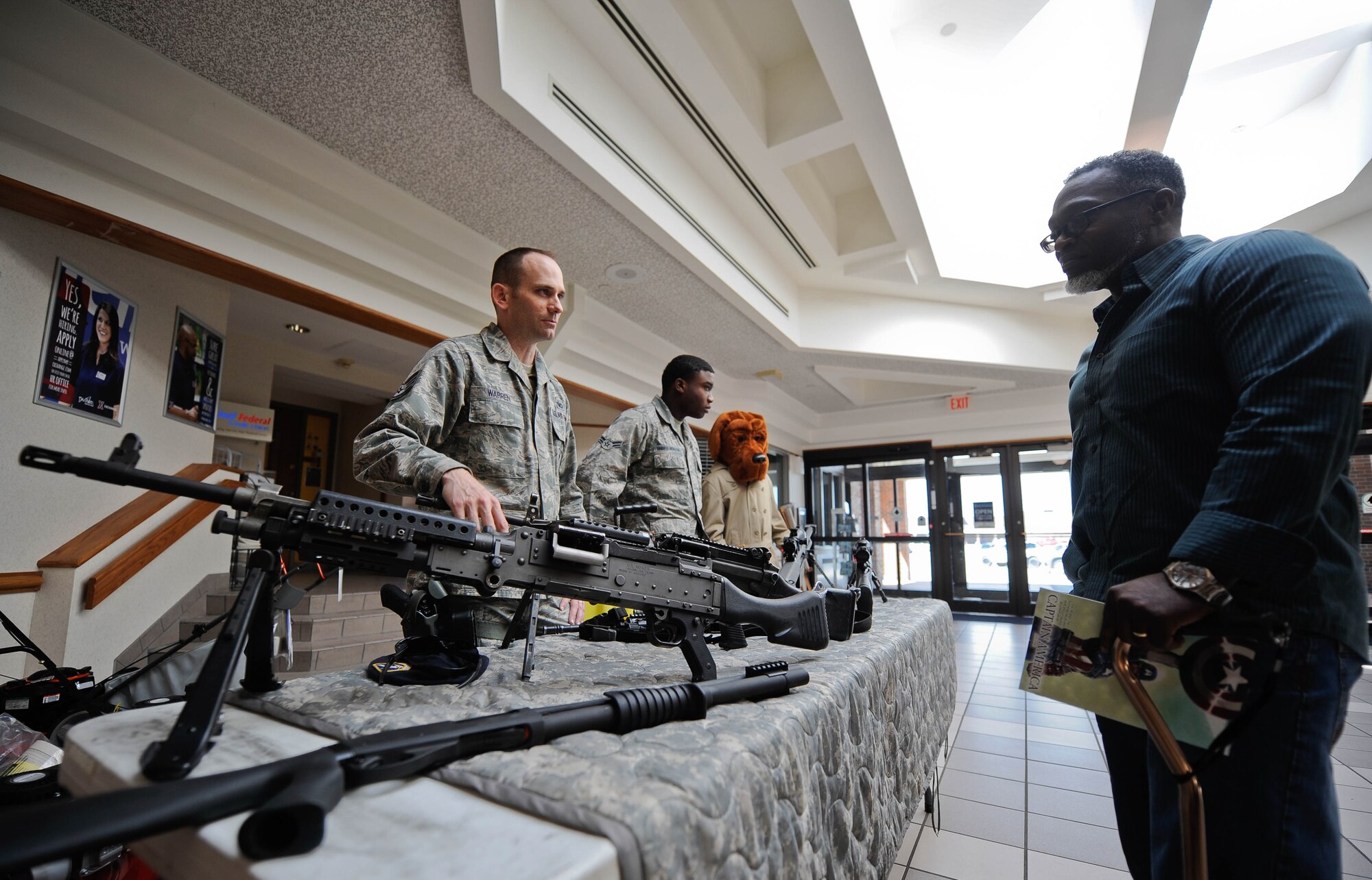 Staff Sgt. Nathan Warren, 28th Security Forces Squadron combat arms instructor, explains the function of a variety of weapons on display in the base exchange at Ellsworth Air Force Base, S.D., May 13, 2014. The display, organized in recognition of National Police Week, helped familiarize Airmen, family members and civilians with the weapons the 28th SFS utilizes on the installation. (U.S. Air Force photo by Senior Airman Zachary Hada/Released)
