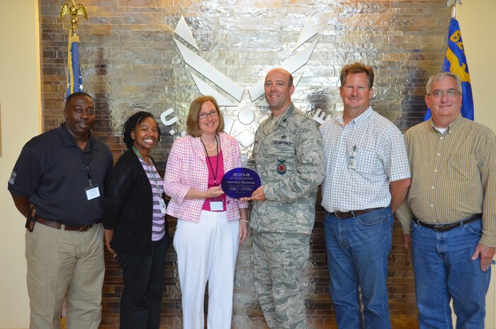 Lt. Col. Patrick Miller, 628th Civil Engineer Squadron commander accepts a plaque from Christine Sanford- Coker, DHEC Area Director LowCountry Environmental Health Services, Charleston Office May 20, 2014, at Joint Base Charleston, S.C. Joint Base Charleston was honored for its comprehensive recycling program that resulted in earning more than $268,000 from the sale of recyclable materials and a reduction in disposal costs of almost $7,000. In addition, the base has a green procurement policy that requires products and services meet high environmental standards regardless of procurement method or purchase value. Along with Miller and Sanford-Coker are (left to right) Edgar Jennings, Charleston County Environmental Management superintendent, Stacey Washington, DHEC Environmental Engineering Associate, Alan Moyer, 628th CES Solid Waste program manager and Dennis Bates, 628th CES Environmental Project Specialist. (U.S. Air Force photo/Eric Sesit)