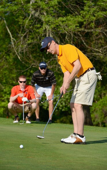 Erik Christensen, food services manager of Mulligan's golf club restaurant, putts toward the hole on the 7th green while his teammates, A1C Ryan Borum, 436th Force Support Squadron, and Lt. Col. Matt Husemann, 436th FSS commander, watch intently on May 15, 2014, at the Eagle Creek golf course on Dover Air Force Base, Del Team Dover along with representatives from local and regional law enforcement agencies participated in a charity tournament during the 2014 Police Week. (U.S. Air Force photo/Greg L. Davis)