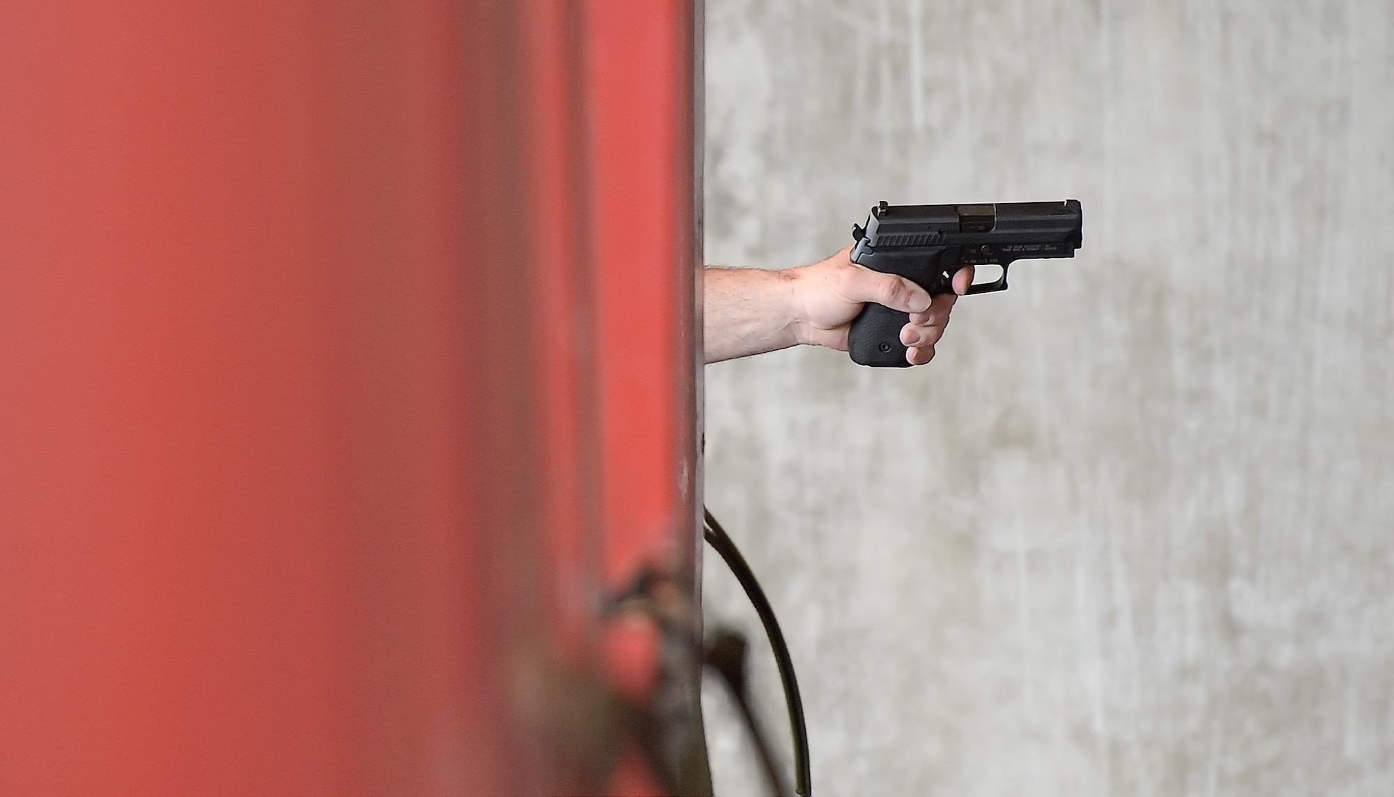 A pistol and forearm protrude from red posts which form shooting stations during the 436th Security Forces Squadron shooting competition May 15, 2014, at Dover Air Force Base, Del. Participants were required to shoot with their weak hand at this station. (U.S. Air Force photo/Greg L. Davis)