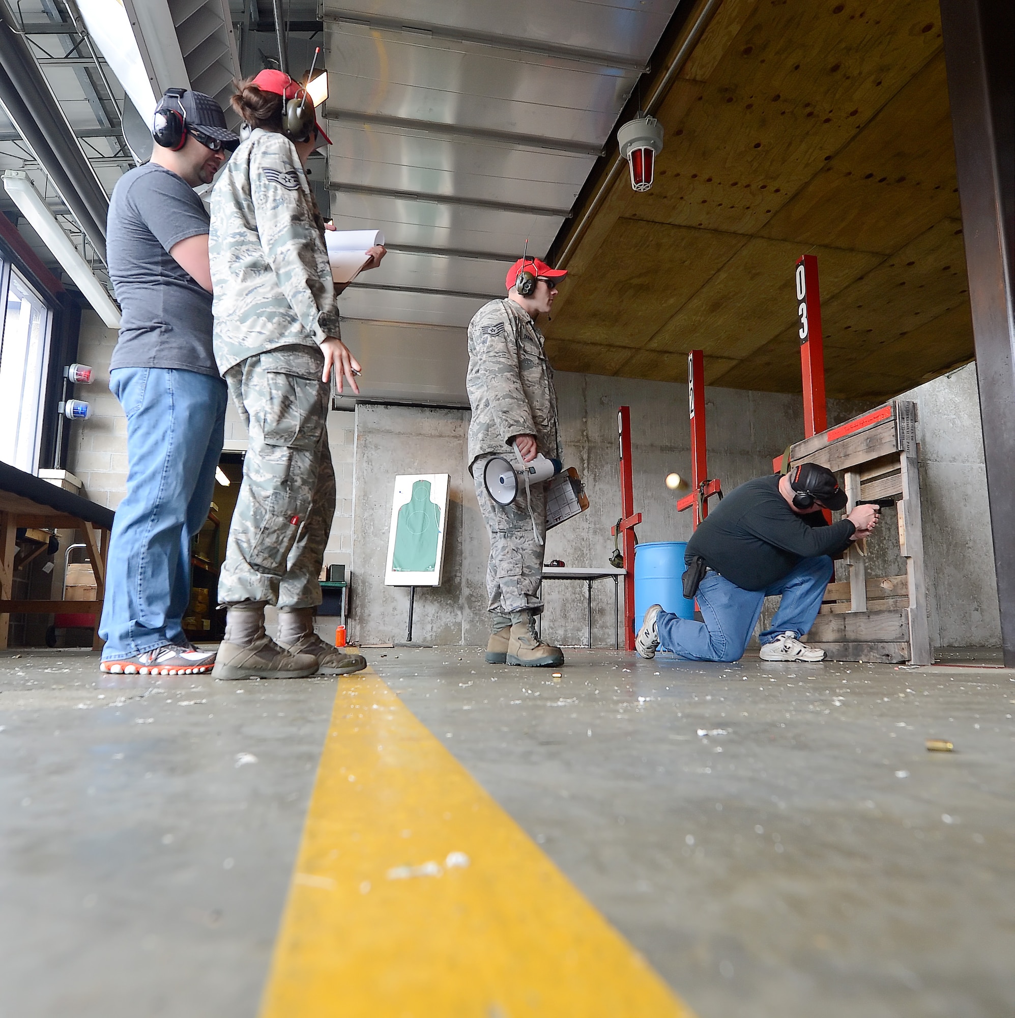 Range safety officials look on during a shooting competition while a law enforcement officer shoots from a kneeling position during a shooting competition hosted by the 436th Security Forces Squadron May 15, 2014, at Dover Air Force Base, Del. Team Dover along with representatives from local and regional law enforcement agencies participated in various events and competitions during the 2014 Police Week. (U.S. Air Force photo/Greg L. Davis)