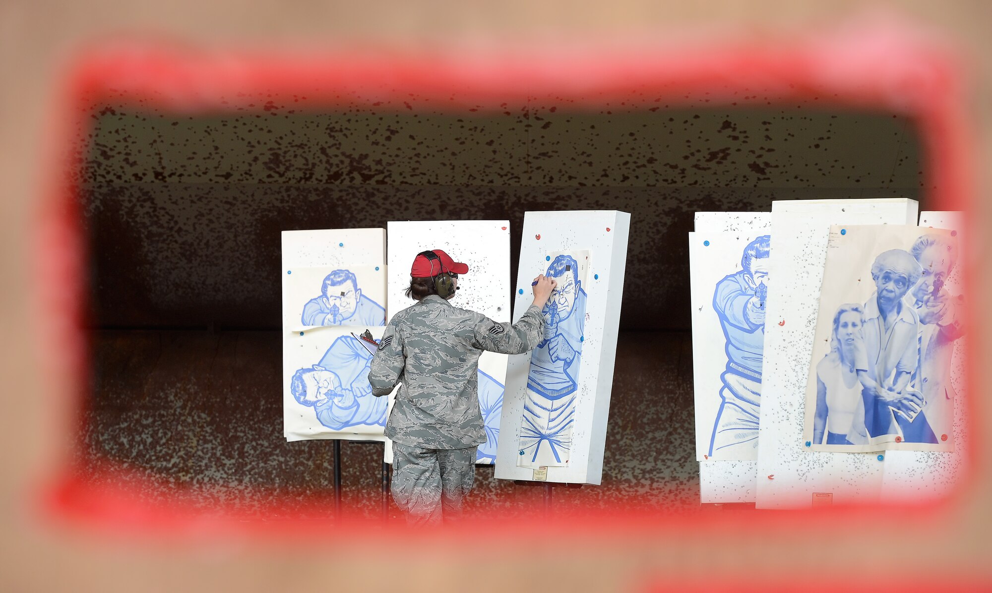 Staff Sgt. Misty Skiles, 436th Security Forces Squadron combat arms instructor, marks-off hits on targets after a competitor has completed a pistol shooting competition May 15, 2014, at Dover Air Force Base, Del. Skiles is framed by an opening in a plywood board at the shooting station for these targets. (U.S. Air Force photo/Greg L. Davis)
