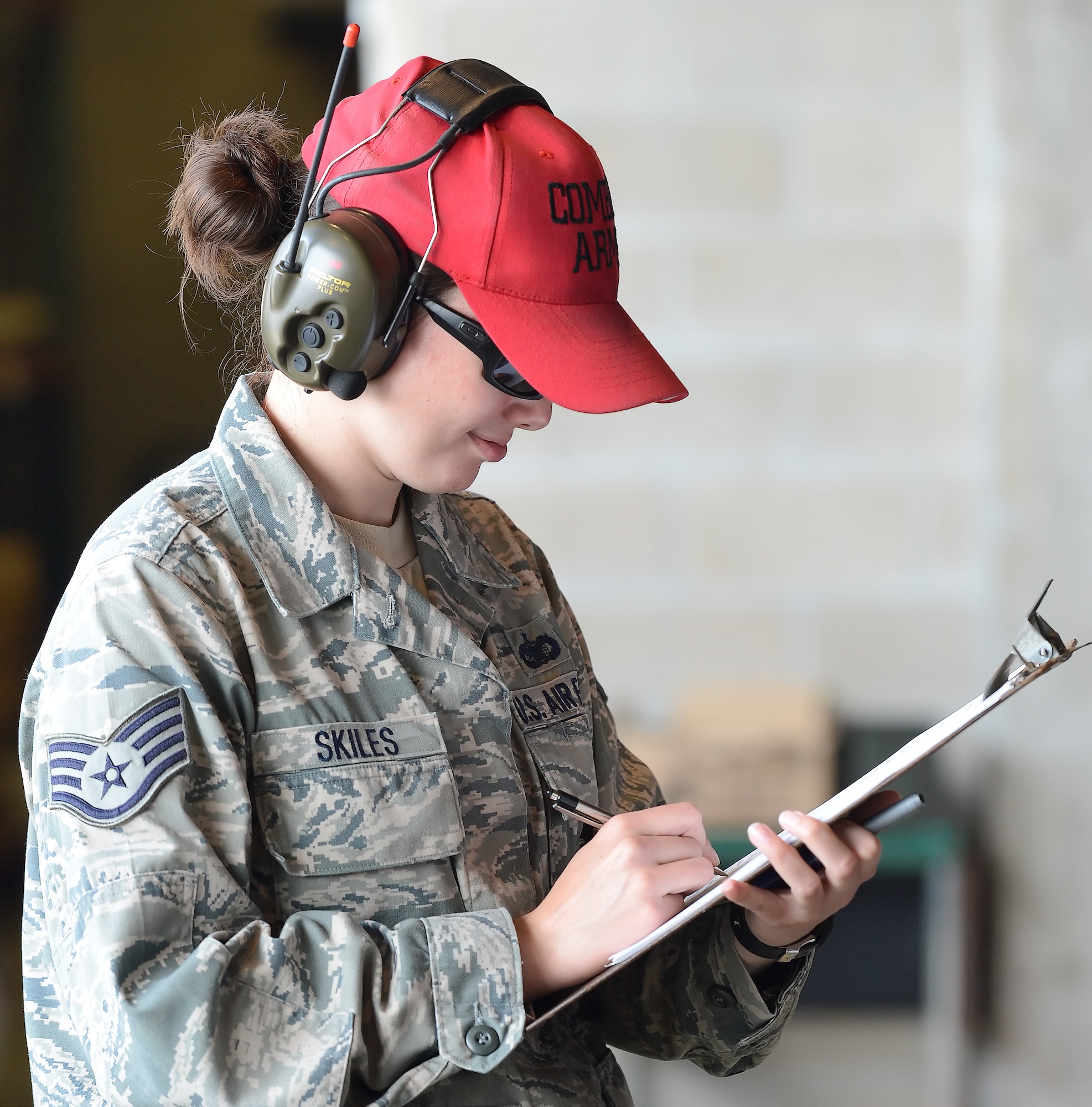 Staff Sgt. Misty Skiles, 436th Security Forces Squadron combat arms instructor, tallies scores after a shooter has completed their time on the range during a pistol shooting competition May 15, 2014, at Dover Air Force Base, Del. Skiles wears a radio communications headset with active-noise reduction built-in along with the bright-red combat arms hat marking her as a range safety supervisor. Team Dover along with representatives from local and regional law enforcement agencies participated in various events and competitions during the 2014 Police Week. (U.S. Air Force photo/Greg L. Davis)