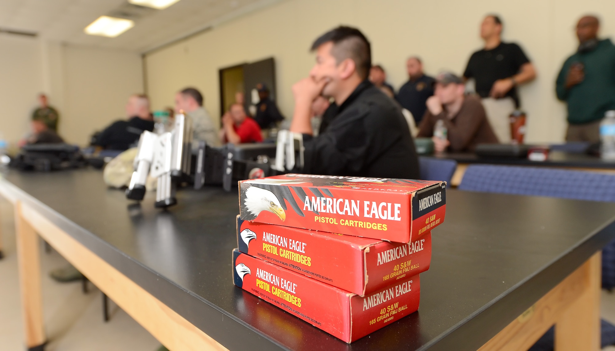 Three boxes of .40-caliber pistol cartridges sit on a table while participants listen to a safety briefing before a shooting competition hosted by the 436th Security Forces Squadron May 15, 2014, at Dover Air Force Base, Del. Team Dover along with representatives from local and regional law enforcement agencies participated in various events and competitions during the week the 2014 Police Week. (U.S. Air Force photo/Greg L. Davis)