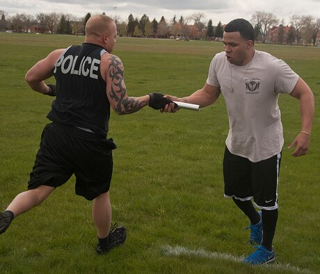 140516-F-GZ967-089 Staff Sgt. Lou Robinson passes a baton to Airman 1st Class Edgar Zarraga, both from the 90th Security Forces Group Tactical Response Force, during the team torture event May 16. As the last obstacle in the relay, each team pushed themselves to make the best times possible. (U.S. Air Force photo by Airman 1st Class Brandon Valle)