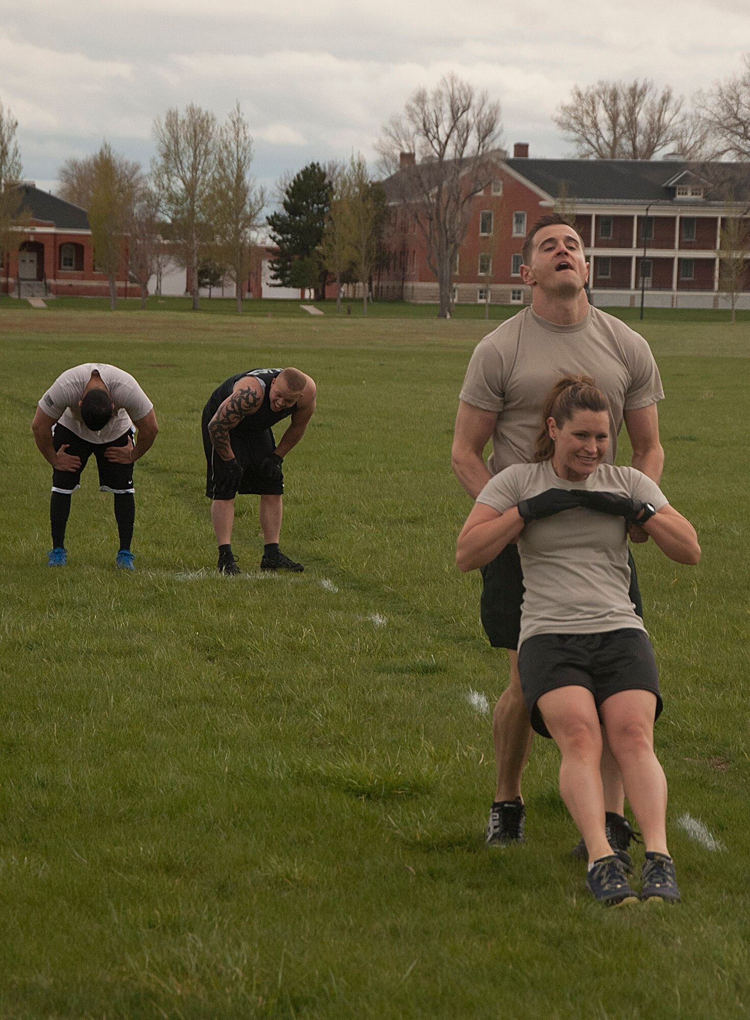 140516-F-GZ967-073 Staff Sgt. Joshua Hansen performs a body drag on Tech. Sgt. Megan Thompson, both from the 90th Security Forces Group Tactical Response Force, during the team torture event May 16 while the second half of his team attempts to catch their breath. The body drag was the third obstacle in the relay. (U.S. Air Force photo by Airman 1st Class Brandon Valle)
