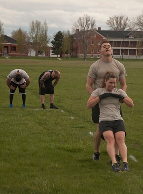 140516-F-GZ967-073 Staff Sgt. Joshua Hansen performs a body drag on Tech. Sgt. Megan Thompson, both from the 90th Security Forces Group Tactical Response Force, during the team torture event May 16 while the second half of his team attempts to catch their breath. The body drag was the third obstacle in the relay. (U.S. Air Force photo by Airman 1st Class Brandon Valle)
