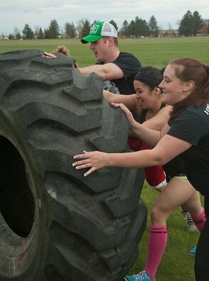 140516-F-GZ967-011 Senior Airman Michael Bailey, 90th Missile Security Forces Squadron; Senior Airmen Julielyn Lew and Monica West, 90th Comptroller Squadron; and Airman 1st Class Jordan Rhodes, 90th Force Support Squadron work together to flip a 500-pound tire during the team torture event May 16.The team had to work together to flip the tire 50 yards before being able to move on to the next obstacle. (U.S. Air Force photo by Airman 1st Class Brandon Valle)