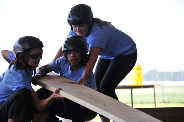 (From left to right) Pam Borgert, the 42nd Mission Support Group commander’s wife, Vanessa Edwards, 42nd Air Base Wing commander’s wife, and Casey Nagaoka Smith, a 42nd Security Forces Squadron key spouse, work together to balance a board above water during a Project X Leadership Reaction Course exercise, May 19, 2014, here. Key Spouses went through the course to strengthen bonds and trust. They also established unique means to problem solving, which they plan to apply helping Airmen here. (U.S. Air Force photo by Staff Sgt. Natasha Stannard)