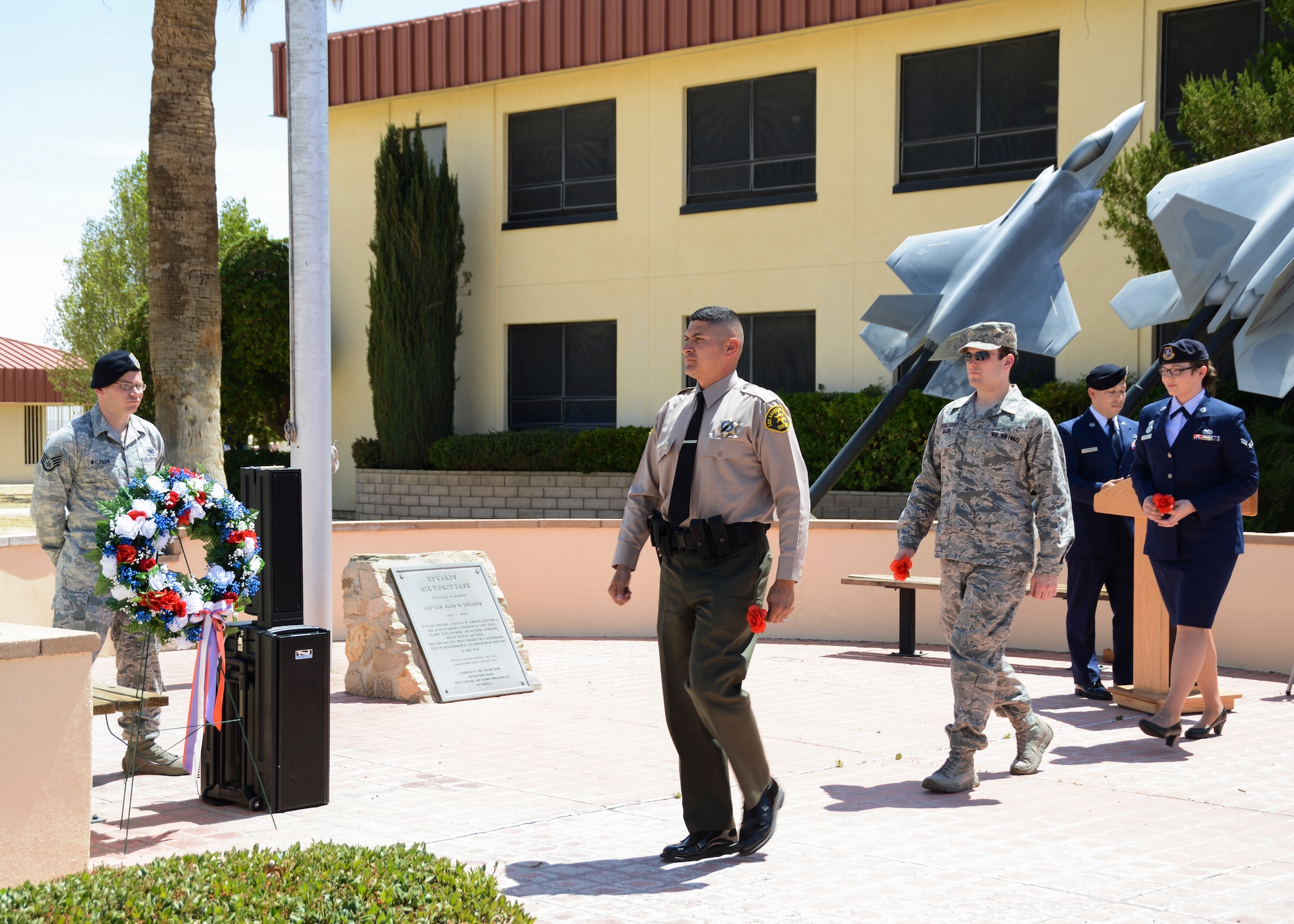 Deputy Ruiz, LA County Sheriffs Department, is followed by Special Agent Ira Collier, Air Force Office of Special Investigations Det 111, and Airman 1st Class Veronica Esparza, 412th Security Forces Squadron, to place a red carnation on a wreath as a reminder of the officers that have died in the line of duty. (U.S. Air Force Photo by Rebecca Amber)