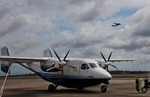 A C-145 Skytruck waits for its next mission while another Skytruck lifts off from the runway at Duke Field Fla. The Aviation Foreign Internal Defense and Skytruck mission is a joint active-duty and reserve Air Force Special Operations Command mission.  (U.S. Air Force photo/Tech. Sgt. Samuel King Jr.)