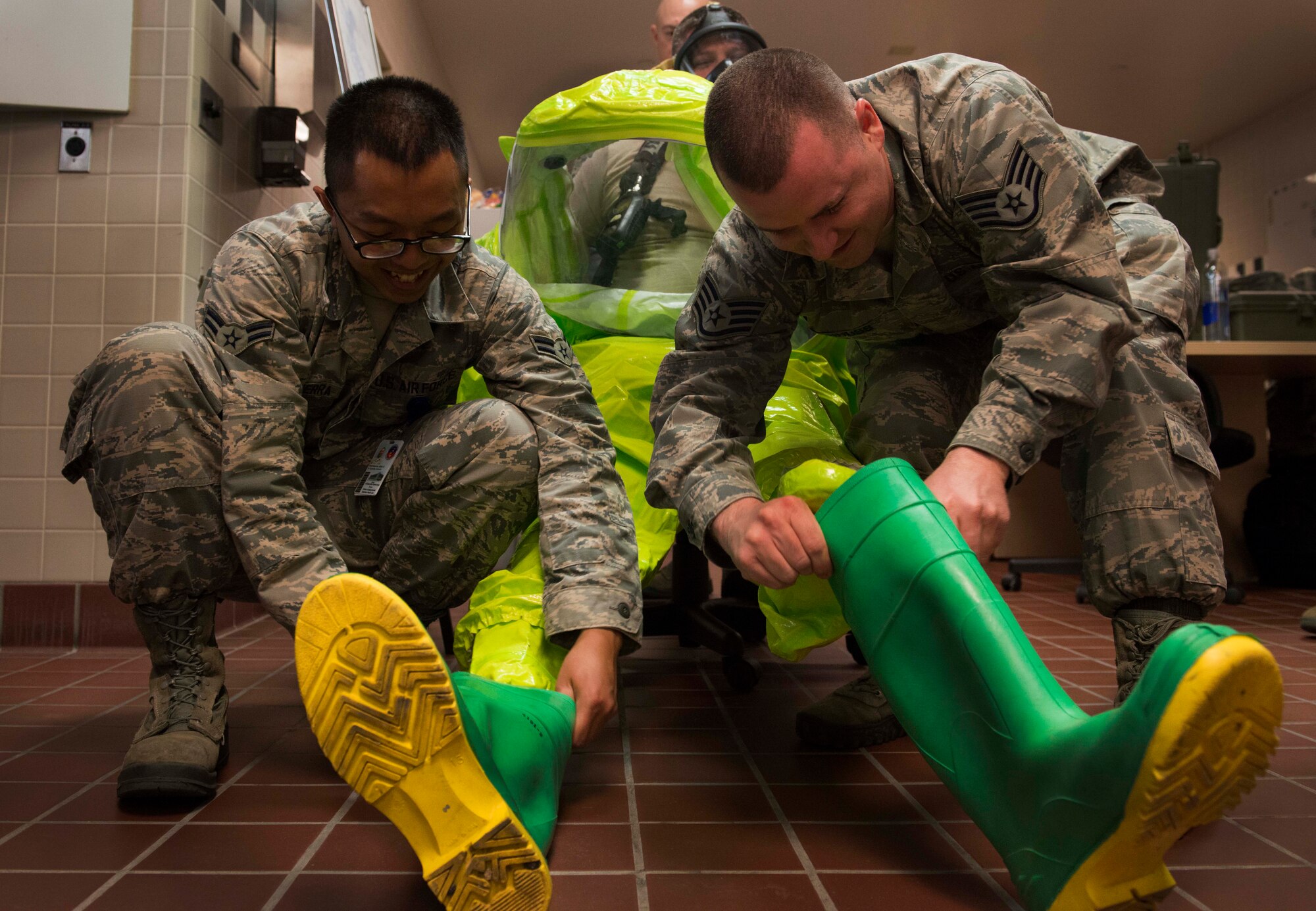 Tech. Sgt Joshua Suggs, 5th Bomb Wing Medical Operations Squadron bioenvironmental engineering technician, is helped into his protective boots by members of his shop at Minot Air Force Base, N.D., May 8, 2014. Suggs and his wingmen are required to recertify their equipment annually. (U.S. Air Force photo/Airman 1st Class Lauren Pitts) 