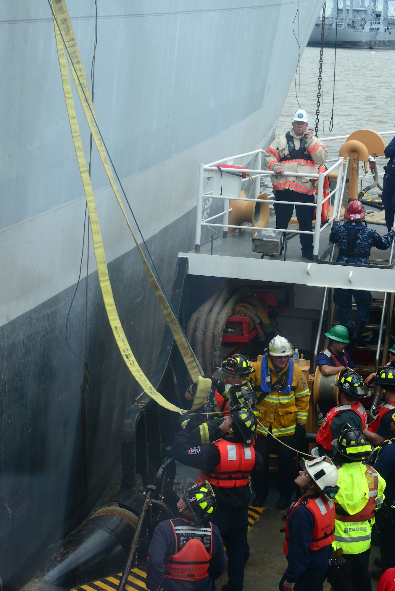 Firefighters on the U.S. Coast Guard Cutter Frank Drew hoist hoses and other items to another ship during the 23rd Annual Hampton Roads Marine Firefighter School at Fort Eustis, Va., May 16, 2014. The class had 113 students from around the world learning how to respond to a ship fire. (U.S. Air Force photo by Airman 1st Class Kimberly Nagle/Released)