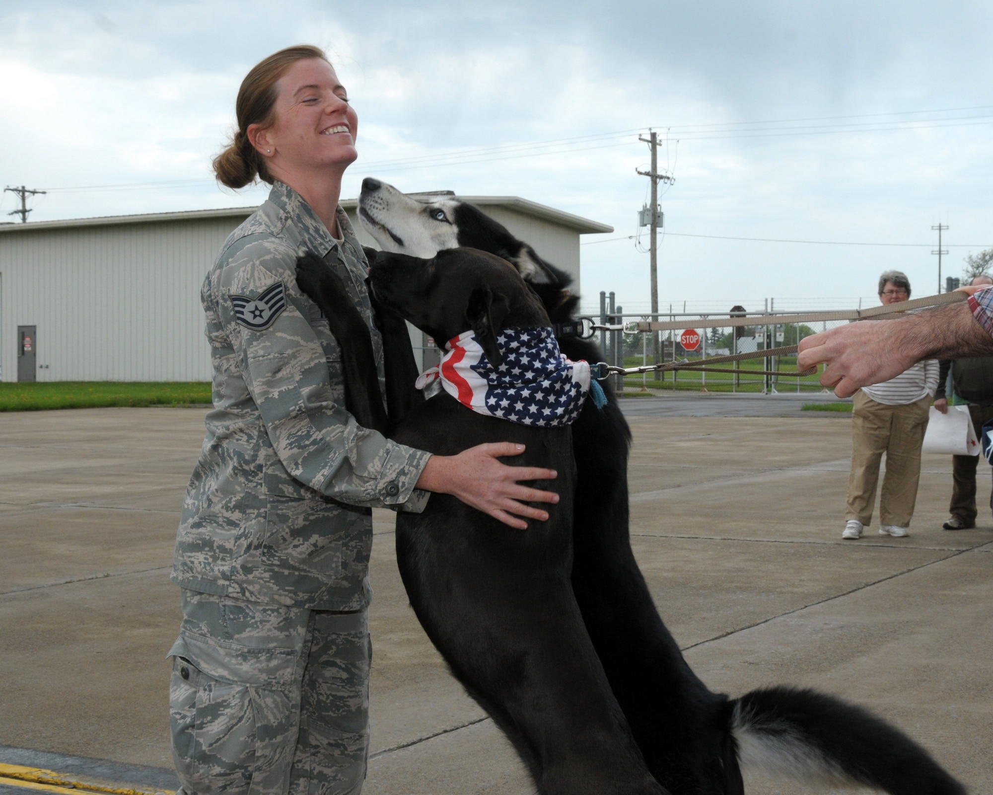 Staff Sgt. Jennifer Trimmer, 914th OSS, aircrew flight equipment specialist receives sloppy kisses from two of her family members  Augey (mixed Lab) and Dagny (Husky)at the Niagara Falls Air Reserve Station, N.Y. May 19, 2014. More than 100 members were deployed overseas recently and have now returned home.  (U.S. Air Force photo by Peter Borys)