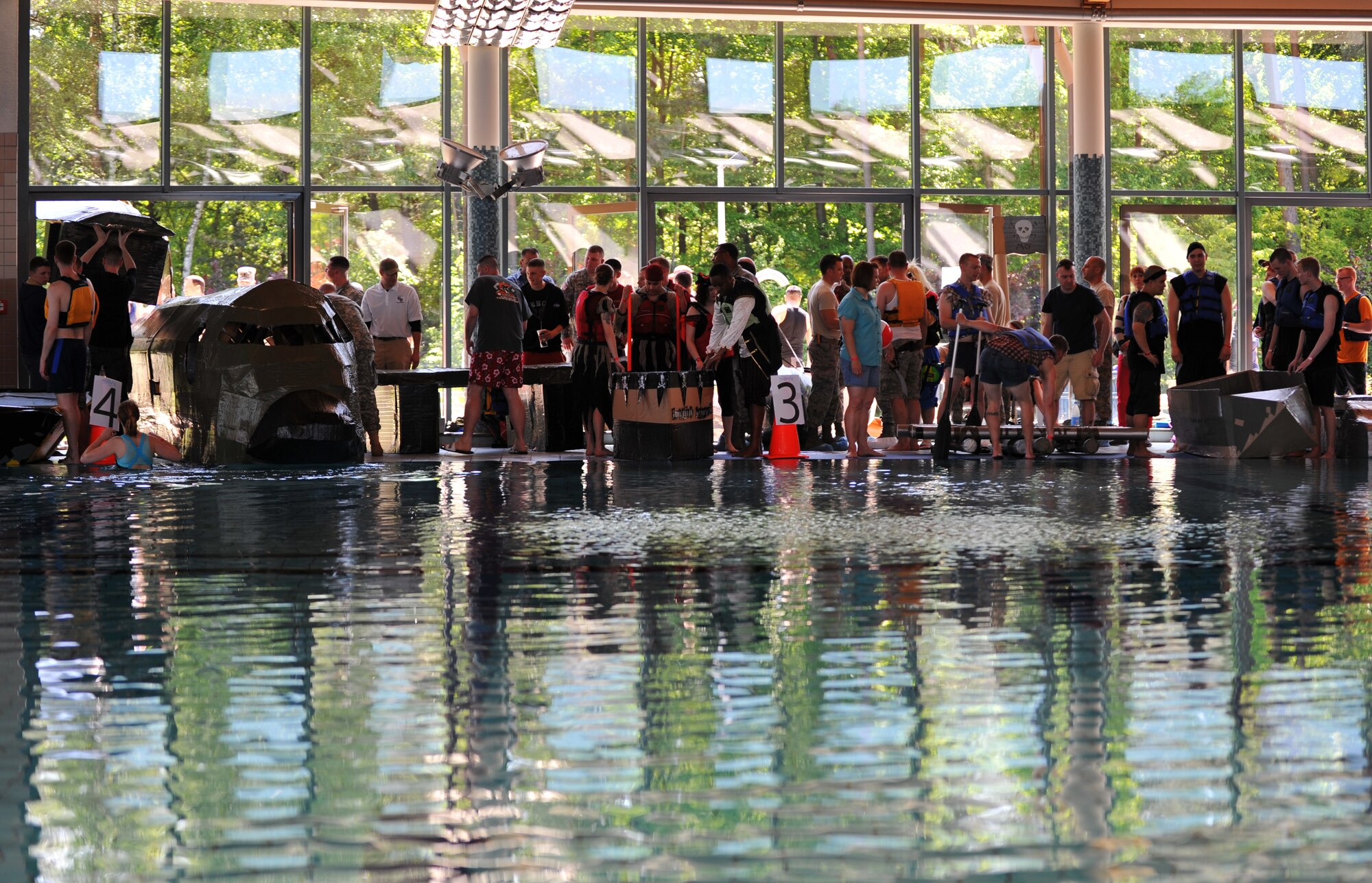 Battle of the Battleships participants prepare themselves and their vessels prior to racing at the base aquatic center on Ramstein Air Base, Germany, May 16, 2014. Battle of the Battleships is an annual competition hosted by the 86th Force Support Squadron in which teams construct boats out of cardboard and duct tape, then race them to and from the other end of the pool. (U.S. Air Force photo/Senior Airman Hailey Haux)