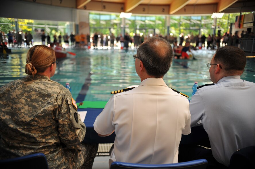 Three judges watch as Battle of the Battleships participants race for the championship title at the base aquatic center on Ramstein Air Base, Germany, May 16, 2014. Battle of the Battleships is an annual competition hosted by the 86th Force Support Squadron in which teams construct boats out of cardboard and duct tape, then race them to and from the other end of the pool. (U.S. Air Force photo/Senior Airman Hailey Haux)