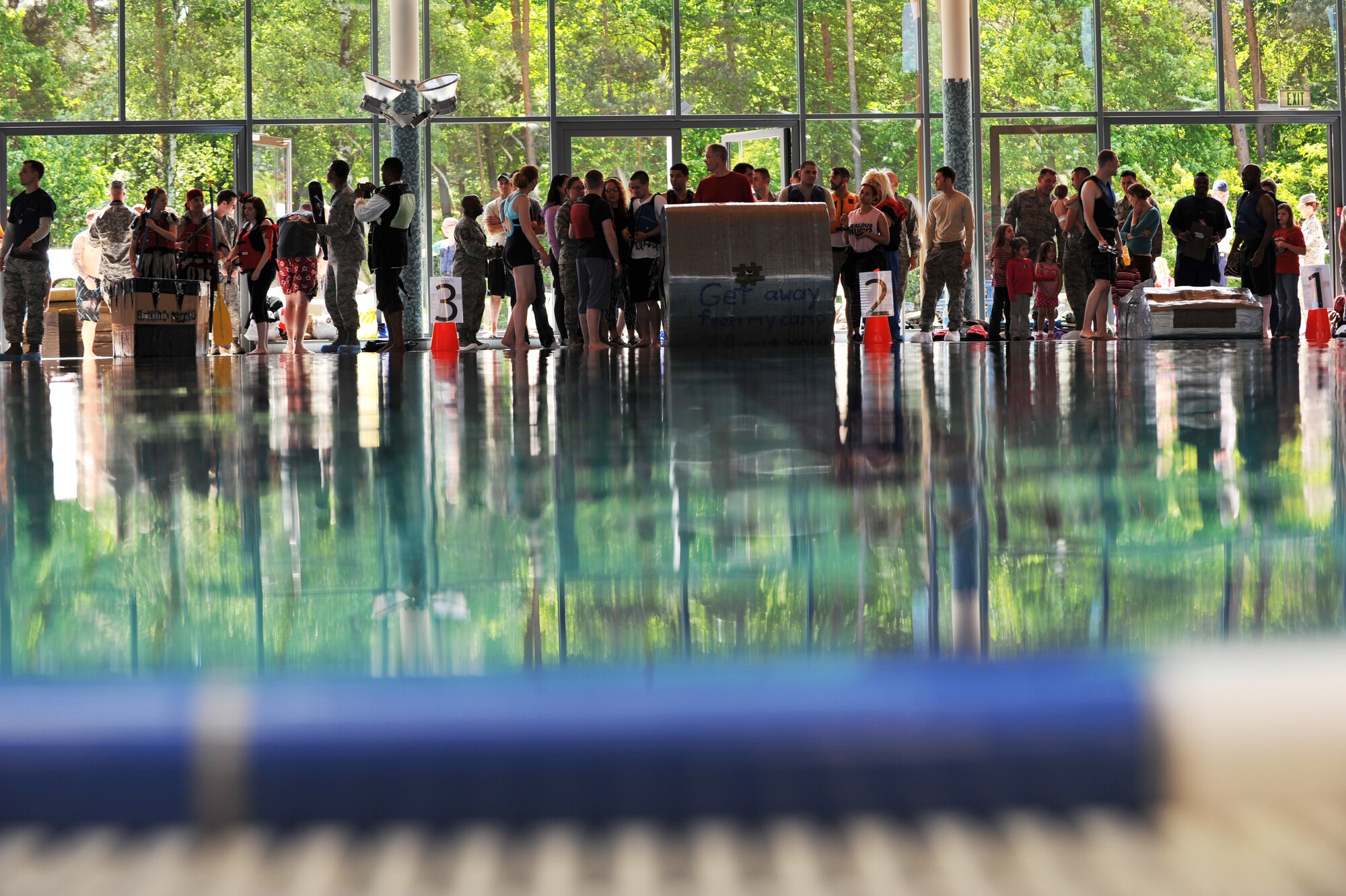 Battle of the Battleships participants prepare themselves and their vessels prior to racing at the base aquatic center on Ramstein Air Base, Germany, May 16, 2014. Battle of the Battleships is an annual competition hosted by the 86th Force Support Squadron in which teams construct boats out of cardboard and duct tape, then race them to and from the other end of the pool. (U.S. Air Force photo/Senior Airman Hailey Haux)
