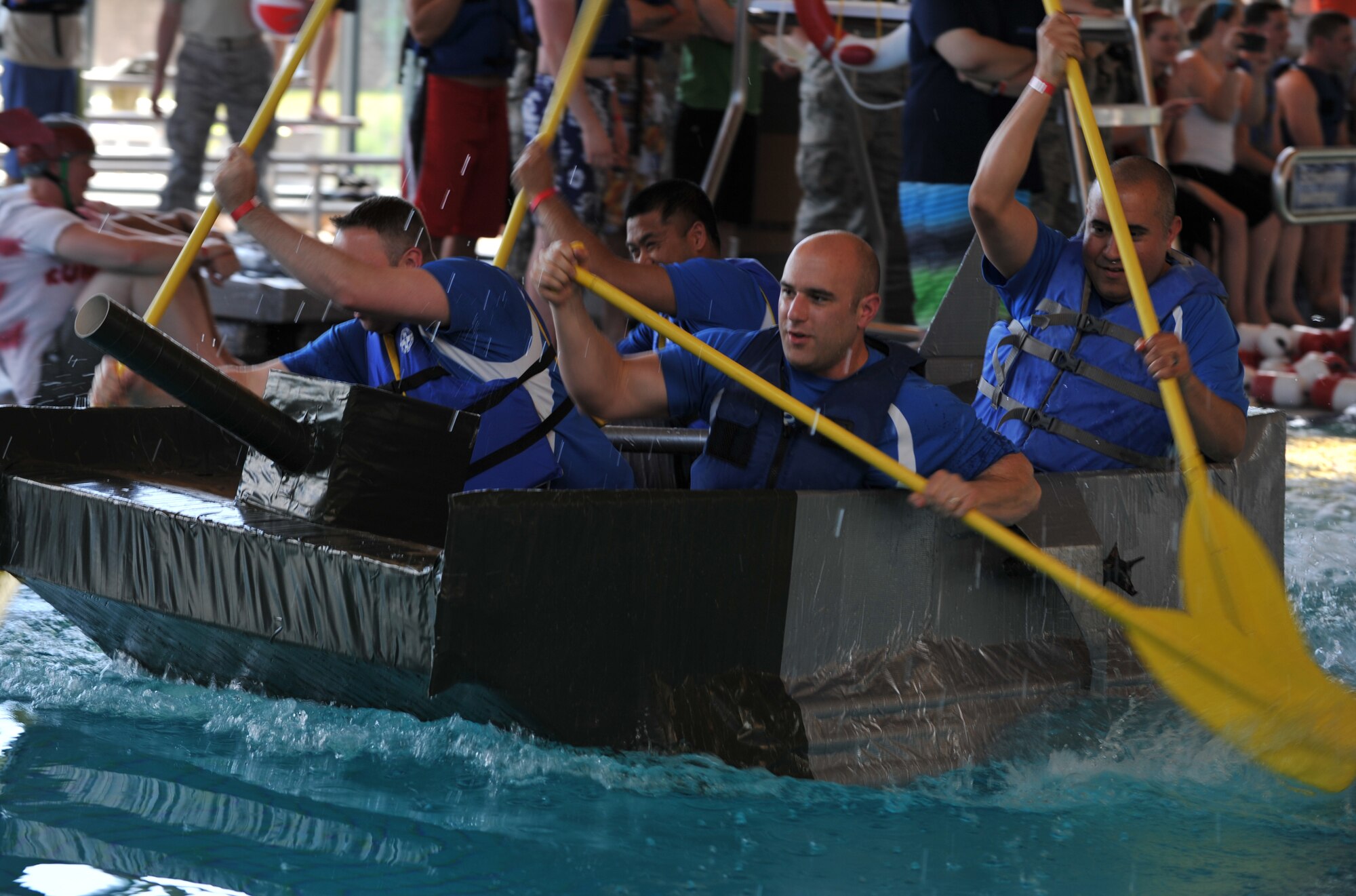 Battle of the Battleships participants paddle to one end of the pool in hopes of being the next winners at the base aquatic center on Ramstein Air Base, Germany, May 16, 2014. Battle of the Battleships is an annual competition hosted by the 86th Force Support Squadron in which teams construct boats out of cardboard and duct tape, then race them to and from the other end of the pool. (U.S. Air Force photo/Senior Airman Hailey Haux)