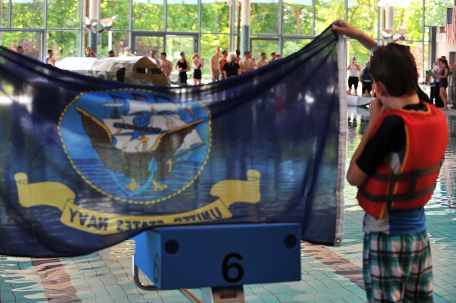 A U.S. Navy flag is flown loud and proud during the Battle of the Battleships competition at the base aquatic center on Ramstein Air Base, Germany, May 16, 2014. Battle of the Battleships is an annual competition hosted by the 86th Force Support Squadron in which teams construct boats out of cardboard and duct tape, then race them to and from the other end of the pool. (U.S. Air Force photo/Senior Airman Hailey Haux)
