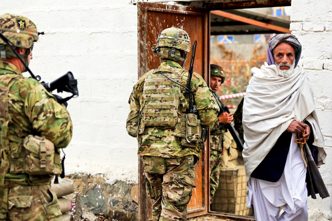 An Afghan man passes members of Provincial Reconstruction Team Farah on their way to the site of a leadership meeting in Farah City, Afghanistan, Jan. 8, 2013.  
