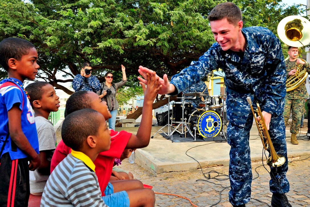 U.S. Navy 2nd Class Kollin Reichow, right, gives a child a high five during a performance in the fishing town of Salamansa ito support Africa Partnership Station in Cape Verde, Jan. 8, 2013. The station is an international security cooperation initiative to strengthen global maritime partnerships through training and collaborative activities in Africa.  
