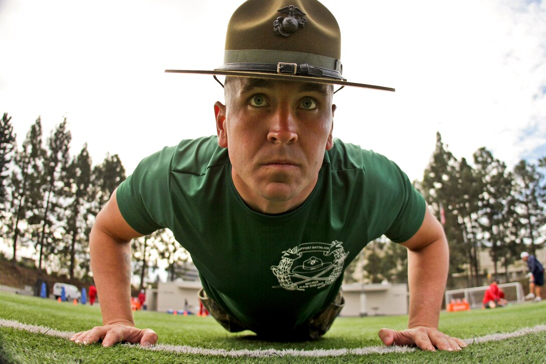 Army Sgt. Mathew Lee perfoms push-ups after watching members of the Semper Fidelis All-American West team exercise at Santa Ana Stadium in Santa Ana, Calif., Jan. 1, 2013. More than 100 football players from across the country will participate in the Semper Fidelis All-American Bowl on Jan. 4, 2013. Lee is a drill instructor.  
