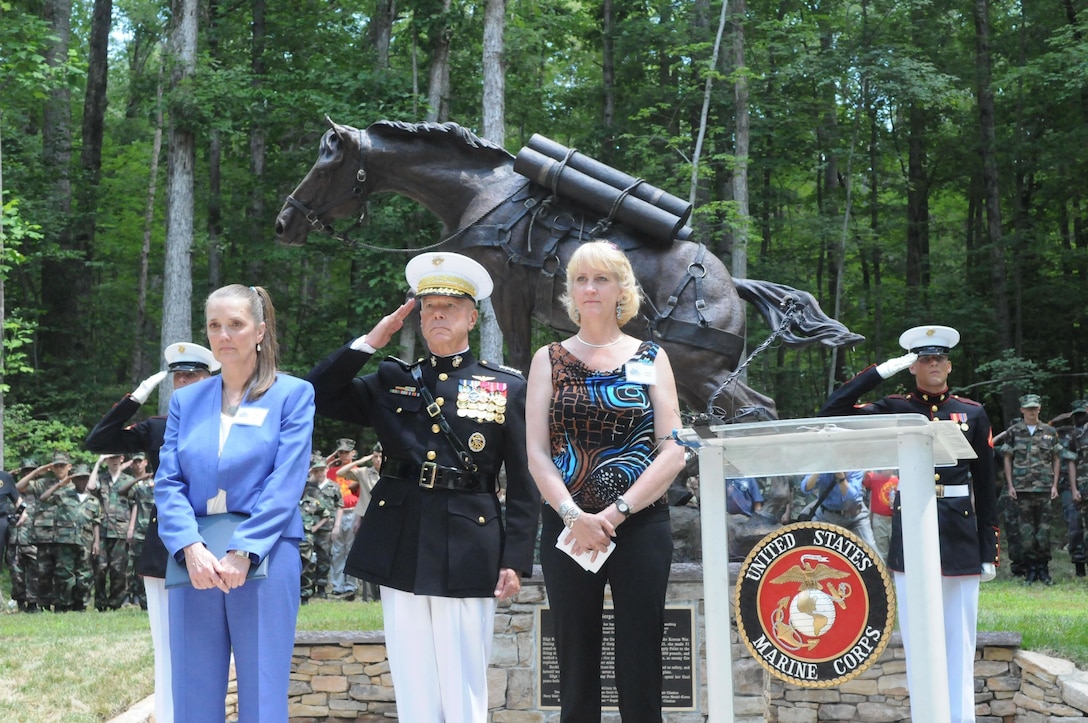 Robin Hutton, founder of the Sgt. Reckless Memorial Fund and the major fundraiser behind the Semper Fidelis Memorial Park’s new statue of Korean War hero Staff Sgt. Reckless, U.S. Marine Corps Gen. James F. Amos, commandant of the Marine Corps, and Jocelyn Russell, the artist who created the statue, stand at attention during the statue’s, unveiling ceremony at the National Museum of the Marine Corps in Triangle, Va., July 26, 2013. Reckless was used during the Korean War to carry ammunition and other supplies to Marines in remote firing positions that were inaccessible to motorized vehicles. (Courtesy Photo by Mike DiCicco/Released)
