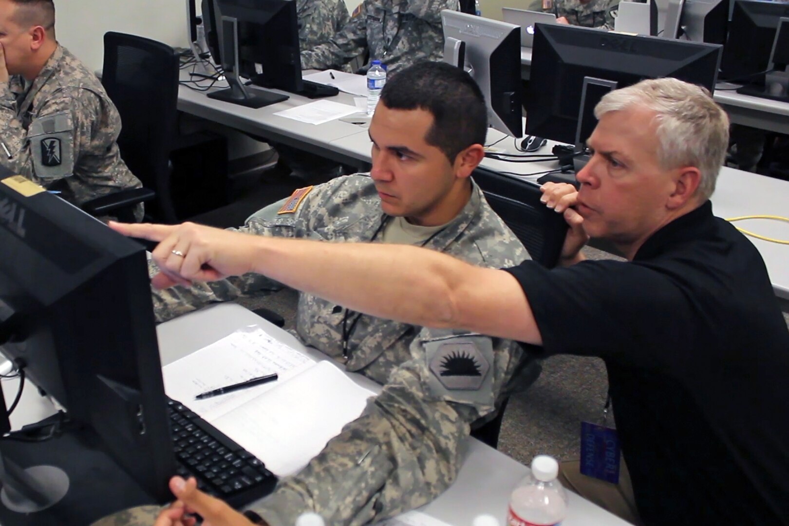 Ken Foster, a computer network analyst with the California Army National Guard Computer Network Defense Team, assists one of his fellow analysts to defend against a simulated virus attack during the 2014 Cyber Shield exercise at the National Guard Professional Education Center in North Little Rock, Ark., April 30, 2014.
