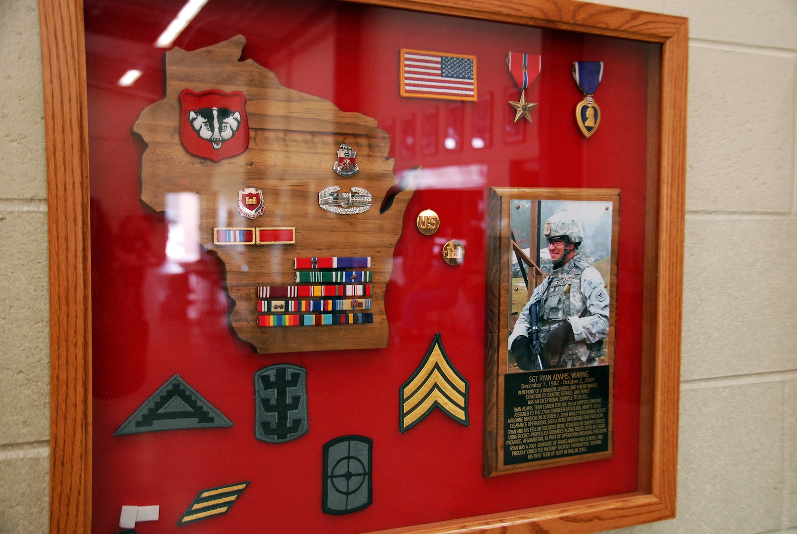 A shadow box dedicated to Sgt. Ryan Adams hangs on a wall in the Army National Guard armory in Rhinelander, Wis., with Adams’ picture and awards. The display serves as a remembrance of his service and sacrifice for fellow Soldiers.