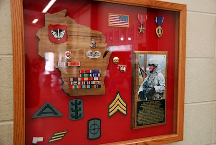 A shadow box dedicated to Sgt. Ryan Adams hangs on a wall in the Army National Guard armory in Rhinelander, Wis., with Adams’ picture and awards. The display serves as a remembrance of his service and sacrifice for fellow Soldiers.