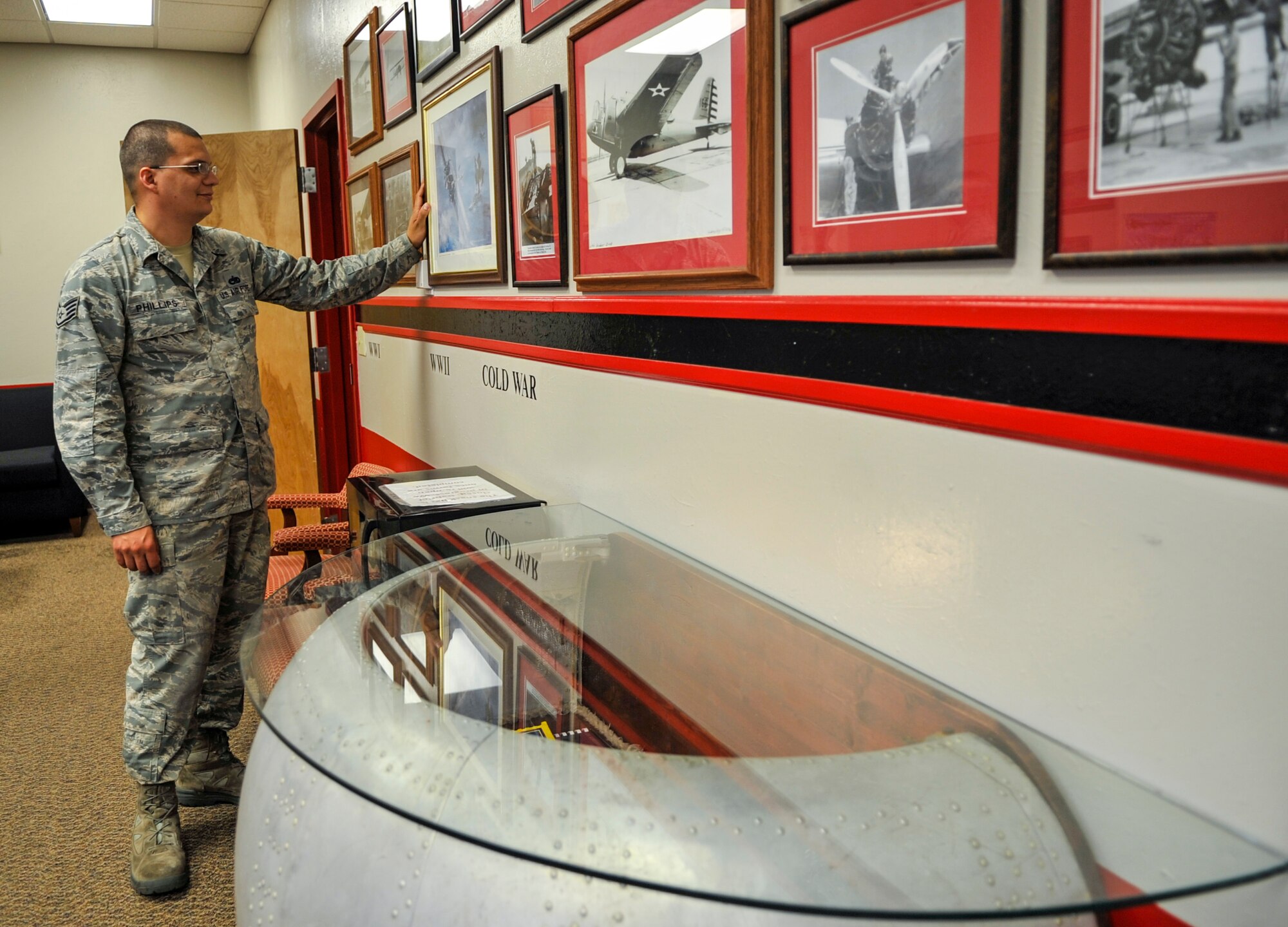 Staff Sgt. Harley Phillips, 2nd Aircraft Maintenance Squadron debrief assistant NCO in-charge, examines a photograph in the 96th Bomb Squadron Heritage Room on Barksdale Air Force Base, La., May 9, 2014. Airmen in the 2nd Aircraft Maintenance Squadron have collected photos, posters and other items as well as donated their time to create the room’s legacy and provide a reminder to Airmen of their storied history. (U.S. Air Force photo/Airman 1st Class Benjamin Raughton)