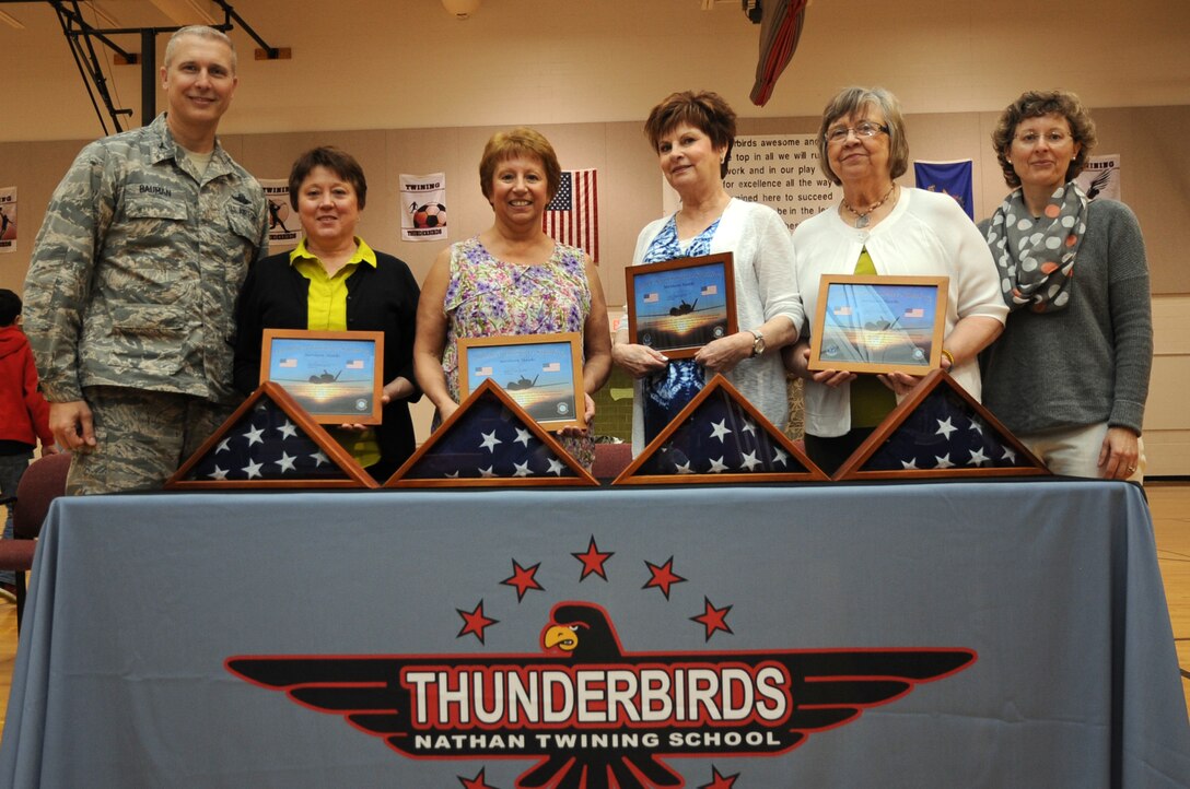 Col. Paul Bauman, 319th Air Base Wing commander, and (far right) Kelly Painter, 319th Force Support Squadron school liaison officer, stand with teachers (from left to right) Patti Patry, Theresa Nordin, Laurel Urbaniak and Karen Griffis in the Nathan W. Twining Elementary and Middle School auditorium on Grand Forks Air Force Base, N.D., May 21, 2014. The four teachers were presented with flags and certificates upon their retirements from the school. Together, they represent more than 100 years of combined service. (U.S. Air Force photo/Staff Sgt. David Dobrydney)