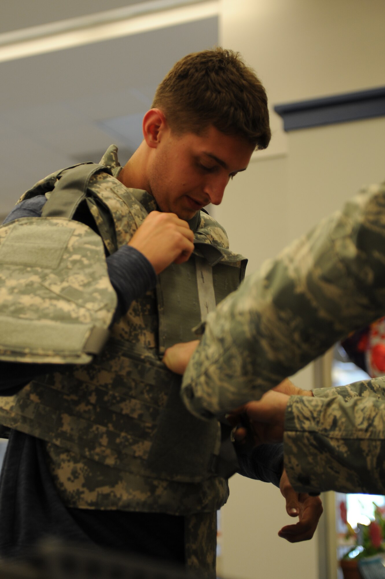 Matt Riley, University of Illinois student, dons a vest with assistance from a security forces Airman at Scott Air Force Base, Ill. on May 15, 2014. The 375th Security Forces Squadron teamed up with police from the surrounding community to educate the public about the purpose of the police and the equipment they employ. (U.S. Air Force photo by Senior Airman Sarah Hall-Kirchner/Released)