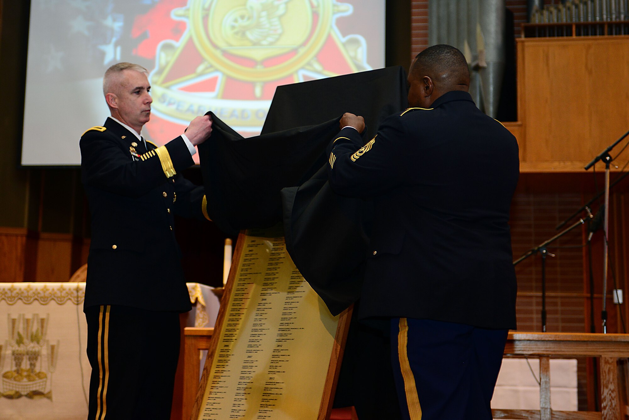 U.S. Army Brig. Gen. John P. Sullivan, Army chief of transportation, and Sgt. Maj. John Pack Jr., Office of the Chief of Transportation sergeant major, unveil the memorial plaque during the Transportation Corps Memorial Wall Rededication Ceremony at Fort Eustis, Va., May 21, 2014. The rededication concluded with a ceremonial bell ringing as each of the 47 names added to the plaque were read aloud. Families, Soldiers and friends were able to render a final salute, paying tribute to the fallen Transportation Corps Soldiers. (U.S. Air Force photo by Staff Sgt. Katie Gar Ward/Released)