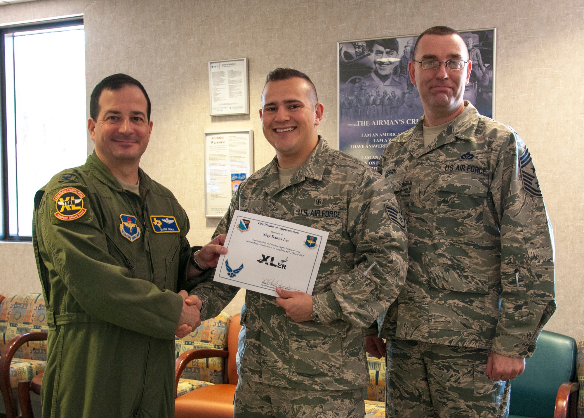 Staff Sgt. Daniel Lee, center, 47th Medical Operations Squadron allergy and immunizations technician, poses with Col. Mark Doria, left, 47th Flying Training Wing vice commander, and Chief Master Sgt. Garry Berry, right, 47th FTW command chief, after being presented the XLer of the week award here May 14, 2014. The XLer is a weekly award chosen by wing leadership and given to those who consistently make outstanding contributions to their unit and Laughlin. (U.S. Air Force photo/Airman 1st Class Ariel D. Delgado/Released)