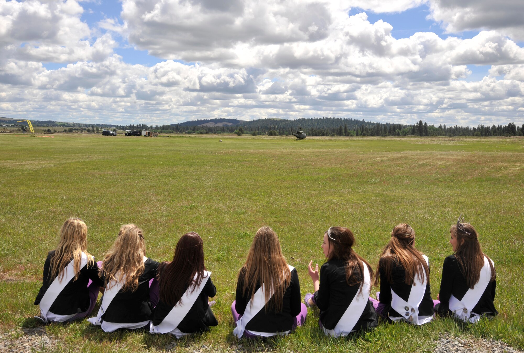 The 2014 Spokane Lilac Princess Royal Court watches on as an UH-1N Iroquois helicopter prepares for take off during parachute training operations at Fairchild Air Force Base, Wash., May 19, 2014. The court was able to watch the demonstrations as well as learn about the different types of parachutes and techniques used to ensure proper training. (U.S. Air Force photo by Senior Airman Mary O'Dell/Released)