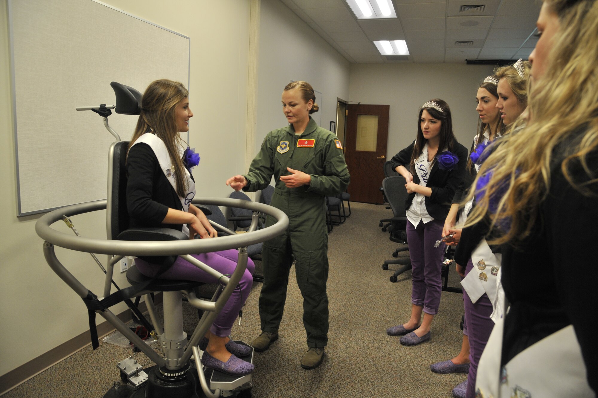 Staff Sgt. Bethany Whiteley demonstrates the Barany chair with Kaylee Pearson during a base tour at Fairchild Air Force Base, Wash., May 19, 2014. The Barany chair is a training tool that helps Airmen understand spatial disorientation and learn to trust their instruments while flying. Whiteley is a 92nd Aerospace Medical Squadron aerospace physiology craftsman and Pearson attends Ferris High School and is the 2014 Spokane Lilac Court Queen. (U.S. Air Force photo by Senior Airman Mary O'Dell/Released)