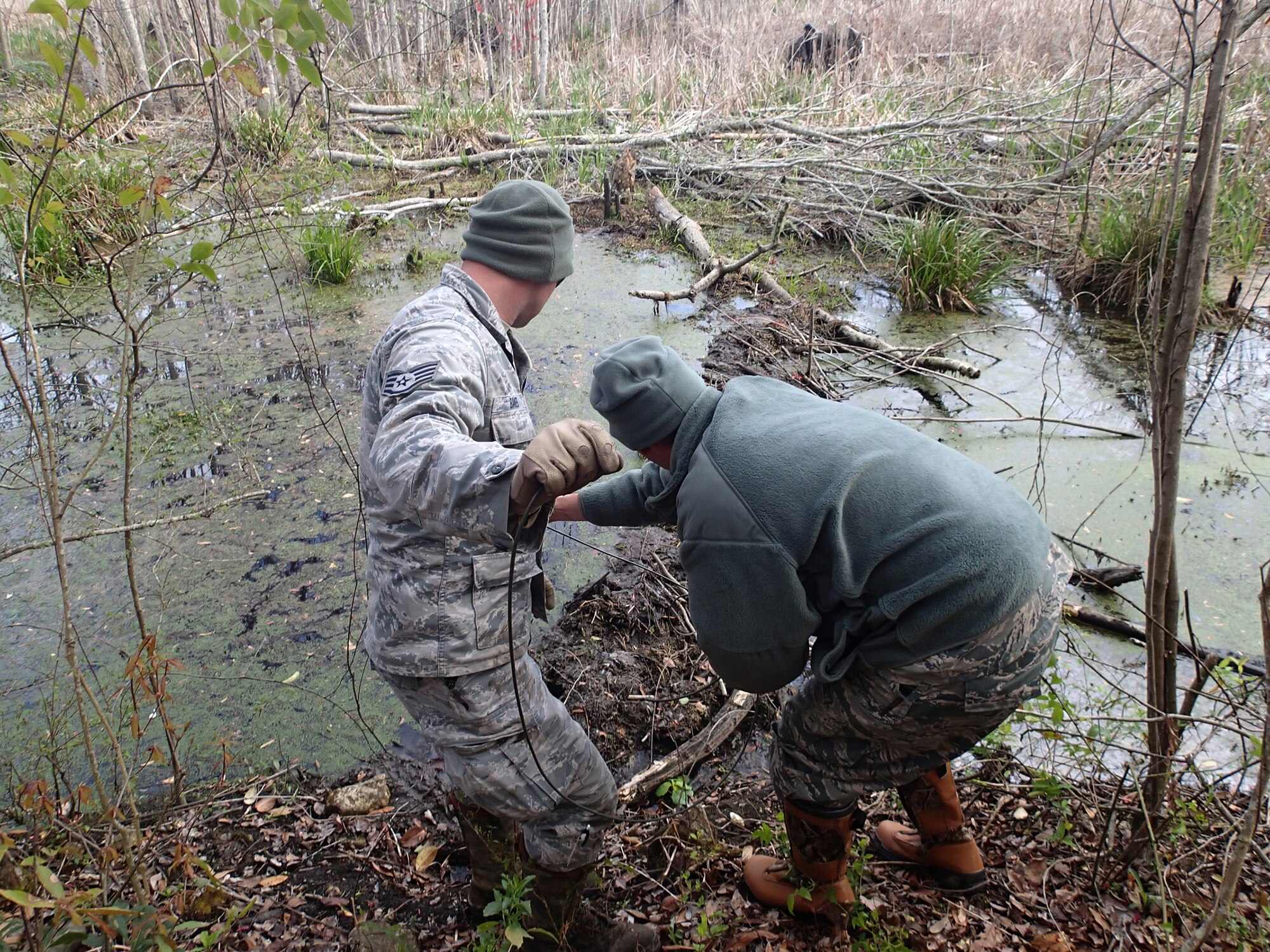 Staff Sgt. Tim Baker of the Kentucky Air National Guard's 123rd Civil Engineer Squadron and Master Sgt. Greg Stephens of the 116th Air Control Wing position detonation cord and C4 explosive to blow up unoccupied beaver dams at Robins Air Force Base, Ga., on April 27, 2014. (Courtesy photo)