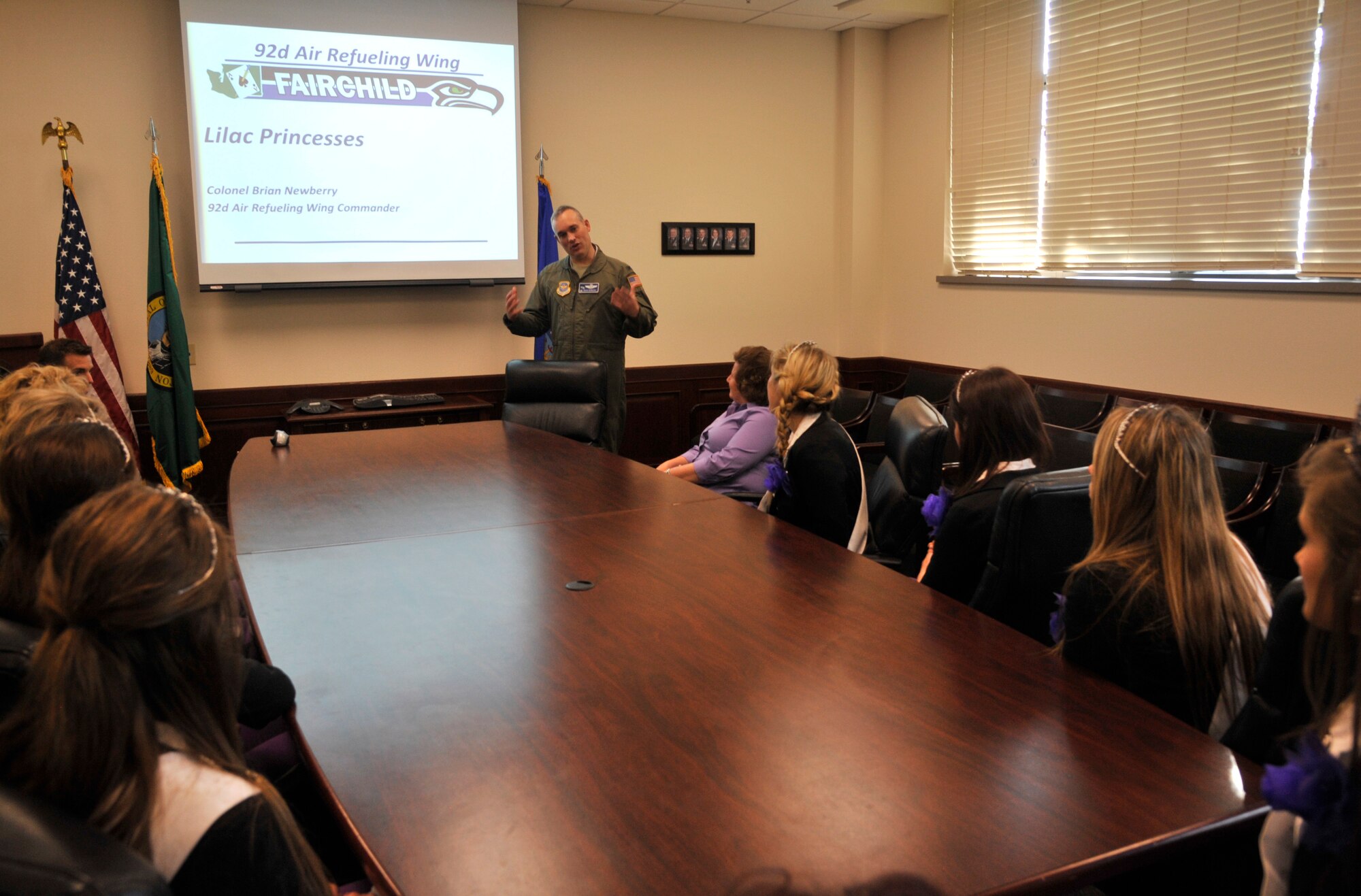 Col. Brian Newberry speaks with the Spokane Lilac Princess Royal Court during a mission briefing at Fairchild Air Force Base, Wash., May 19, 2014. The briefing was a part of a base tour held to showcase the Team Fairchild mission. During the tour, the court visited students at Michael Anderson Elementary School, aerospace physiology, the Survival, Evasion, Resistance and Escape parachuting facility and more. Newberry is the 92nd Air Refueling Wing commander. (U.S. Air Force photo by Senior Airman Mary O'Dell/Released)