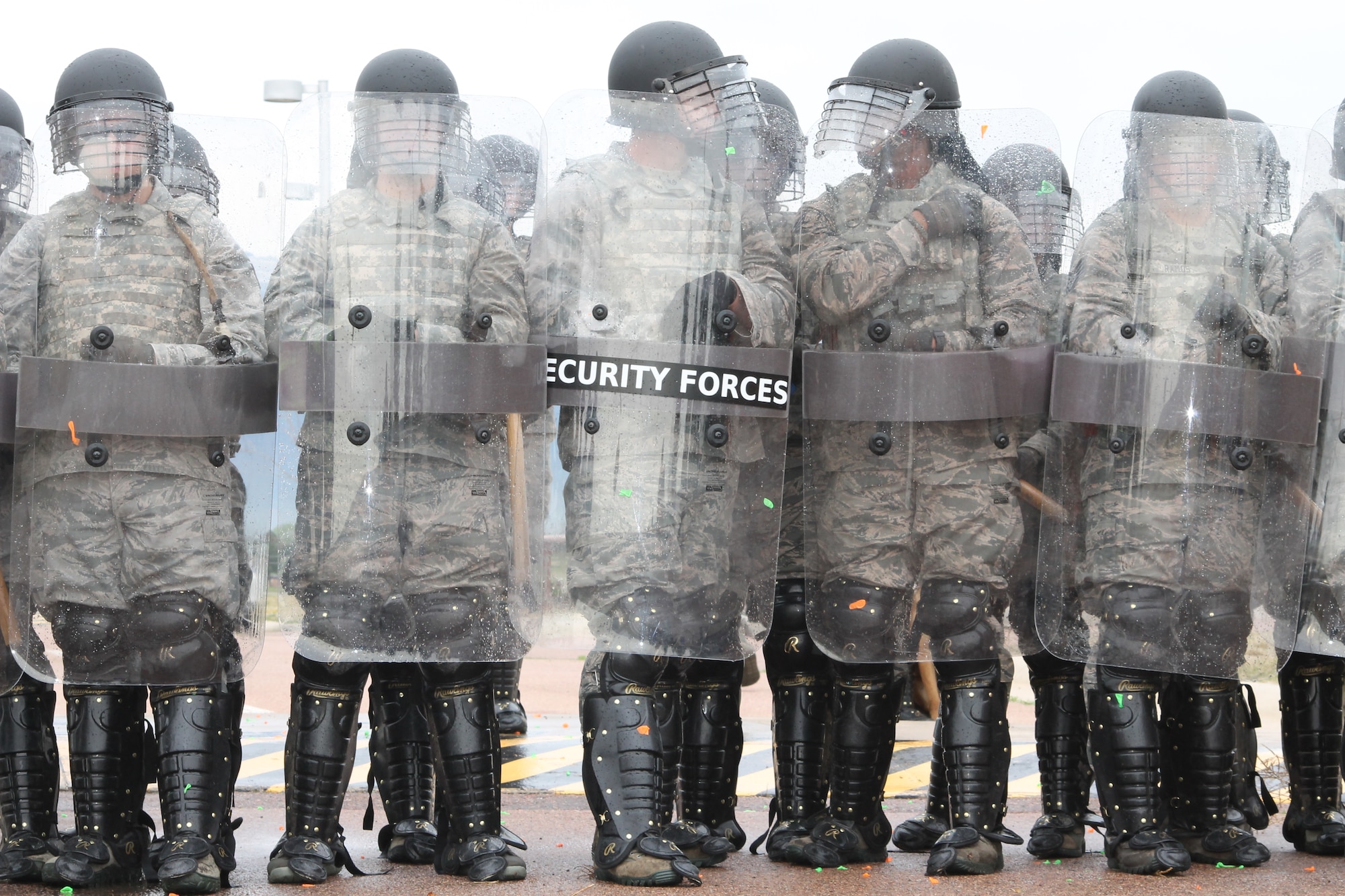PETERSON AIR FORCE BASE, Colo. – Airmen from the 21st Security Forces Squadron wearing protective riot gear form a barrier against a crowd of unruly protesters during the Condor Crest exercise May 9. The quarterly exercise is designed to test and evaluate base readiness for real-word events. The exercise culminated in a mock explosion at the 21st Medical Group headquarters building which allowed emergency responders from security forces, the medical group, civil engineering and others to rehearse their interaction and collaboration in response to the crisis. (U.S. Air Force photo/Michael Golembesky)