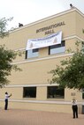 Senior Airman Keeland Hill (left) and Annette Janetske unveil the new name for the Defense Language Institute English Learning Center headquarters building, International Hall. (U.S. Air Force photo by Johnny Saldivar/ released)