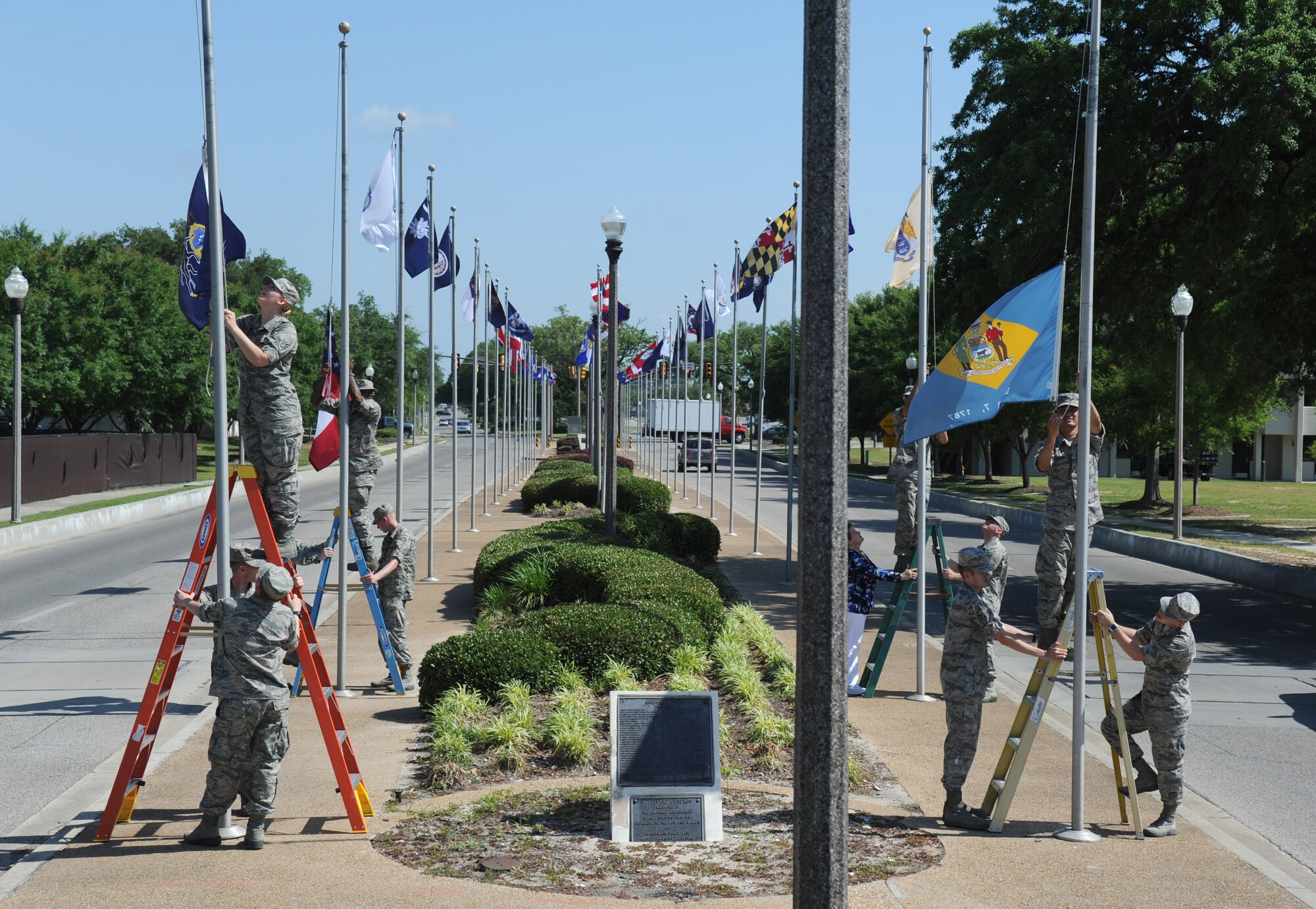 Technical training students volunteer to hang one of the two sets of flags that were donated to the 81st Training Wing by the Biloxi Chamber of Commerce May 20, 2014, on Larcher Blvd., at Keesler Air Force Base, Miss. (U.S. Air Force photo by Kemberly Groue)
