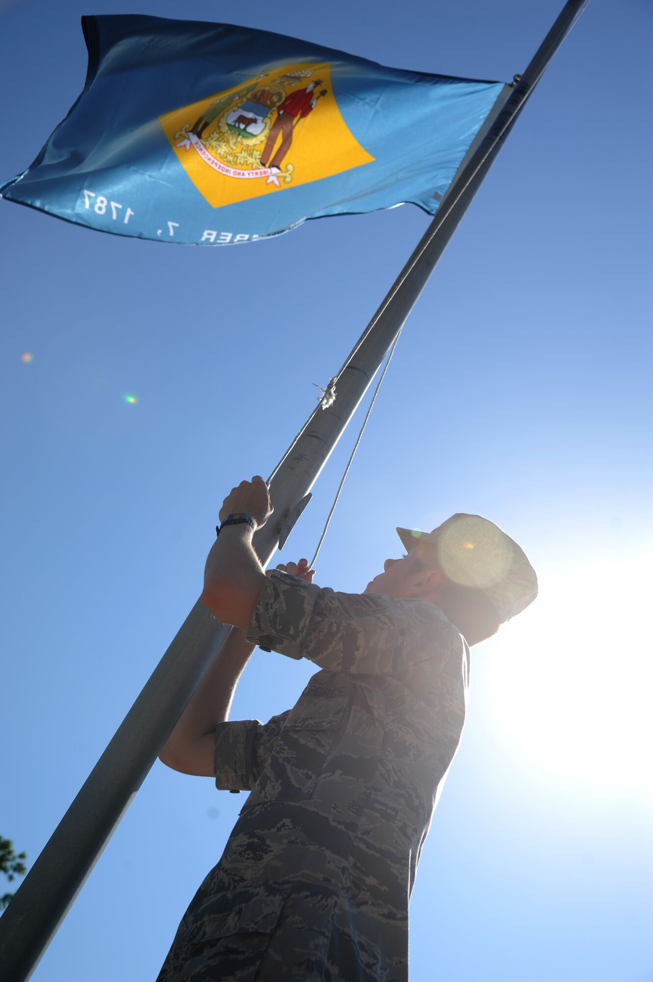 Airman 1st Class Jacob Miller, 336th Training Squadron, raises the Delaware state flag May 20, 2014, on Larcher Blvd., at Keesler Air Force Base, Miss.  Technical training students volunteered to hang one of the two sets of donated flags to the 81st Training Wing by the Biloxi Chamber of Commerce. (U.S. Air Force photo by Kemberly Groue)