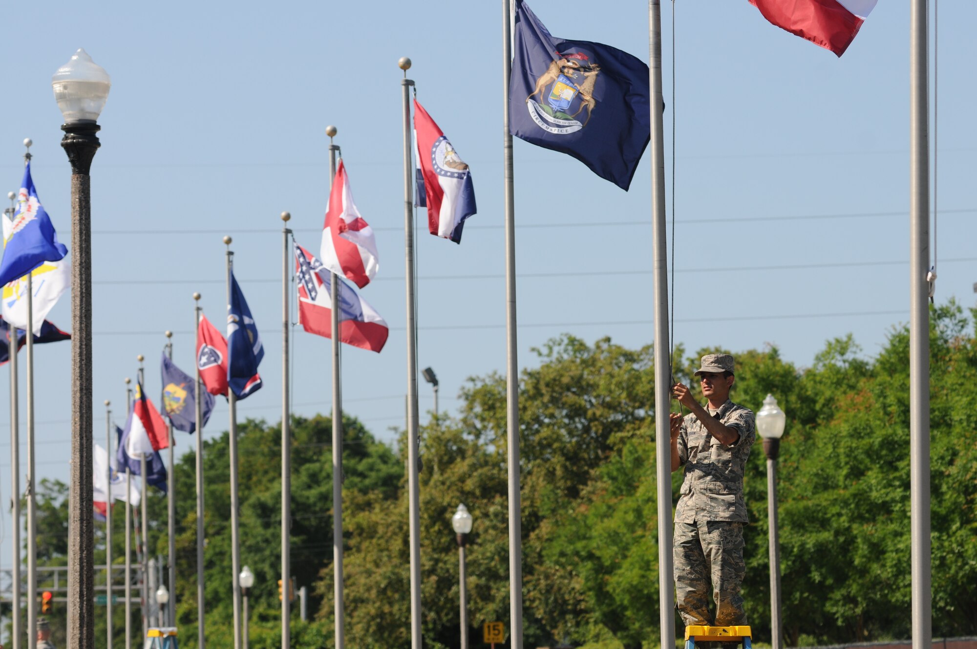 Airman 1st Class Ken Isham, 336th Training Squadron, secures the rope after raising one of the state flags May 20, 2014, on Larcher Blvd., at Keesler Air Force Base, Miss.  Technical training students volunteered to hang one of the two sets of flags that were donated to the 81st Training Wing by the Biloxi Chamber of Commerce. (U.S. Air Force photo by Kemberly Groue)