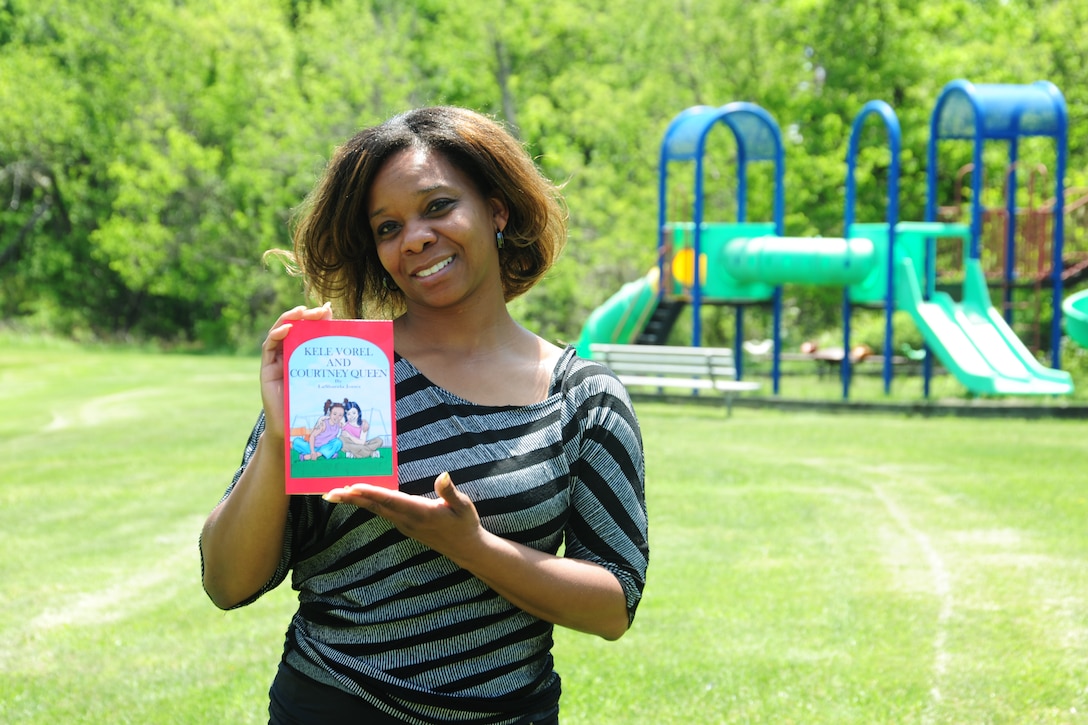 LaShanda Jones, holds a copy of her first published childrens' book, "Kele Vorel and Courtney Queen" on May 19, 2014, in front of the Joint Base Andrews, Md.,459th Air Refueling Wing playground. Jones, a retired Air Force veteran, is the chief of finance at the wing. (U.S. Air Force photo / Amber J. Russell)