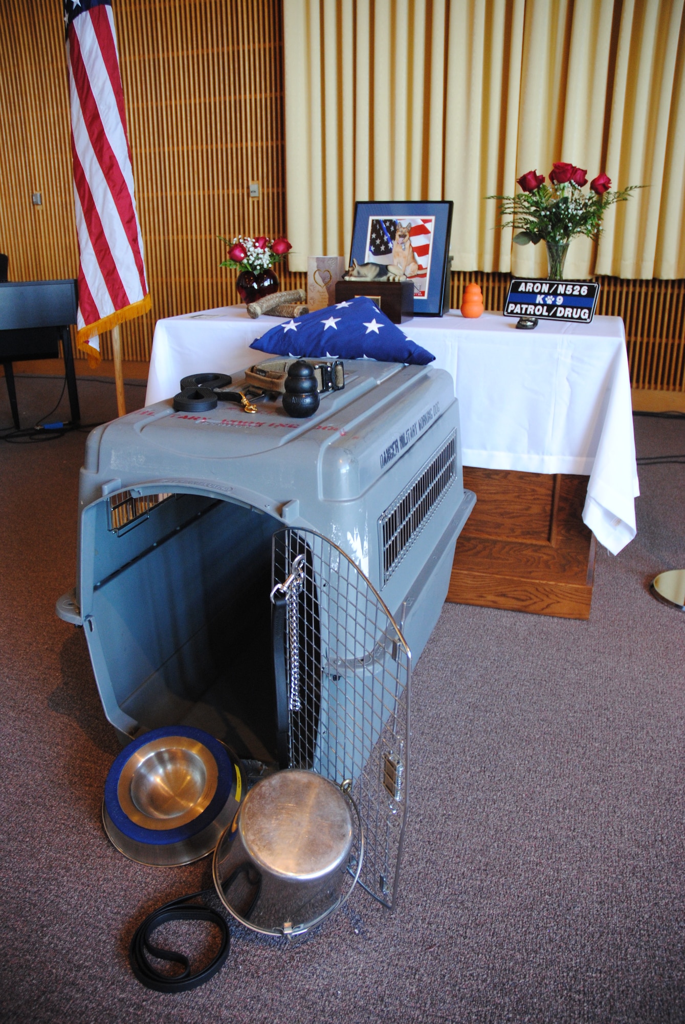 Members of the 319th Security Forces Squadron Military Working Dog Section placed an empty kennel as part of a physical tribute created in honor of Military Working Dog Aron for a memorial service held May 15, 2014, at the Prairie Rose Chapel on Grand Forks Air Force Base, N.D. The leash on the door symbolizes the everlasting eternal bond between dog and handler. The empty kennel represents the life that our four-legged comrades gave in service to our country. (U.S. Air Force photo/Staff Sgt. Luis Loza Gutierrez) 

