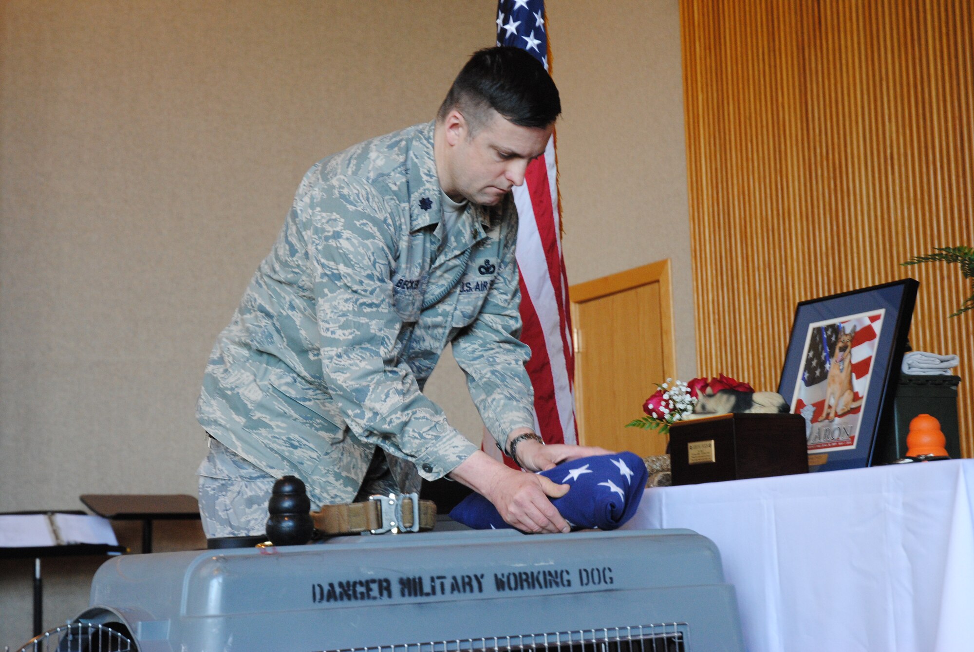 Lt. Col. Jeffrey Becker, 319th Security Forces Squadron commander, lays a folded U.S. flag near the urn containing the remains of Military Working Dog Aron during a memorial service held in honor of the canine on May 15, 2014, at the Prairie Rose Chapel on Grand Forks Air Force Base, N.D. Aron, a Belgian Malinois, served as a patrol narcotics detector dog, and was humanely euthanized on May 7, 2014, after it was discovered he was dying of cancer. (U.S. Air Force photo/Staff Sgt. Luis Loza Gutierrez) 
